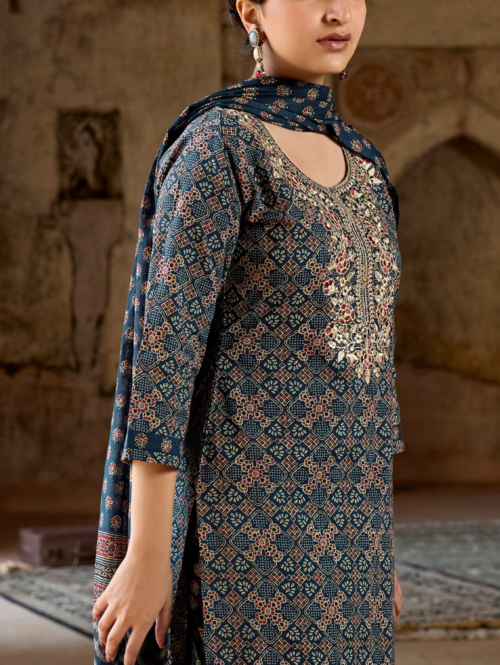 A woman wearing a green and white embroidered pure cotton suit set with three-quarter sleeves and side slits, including straight pants and a printed cotton dupatta.