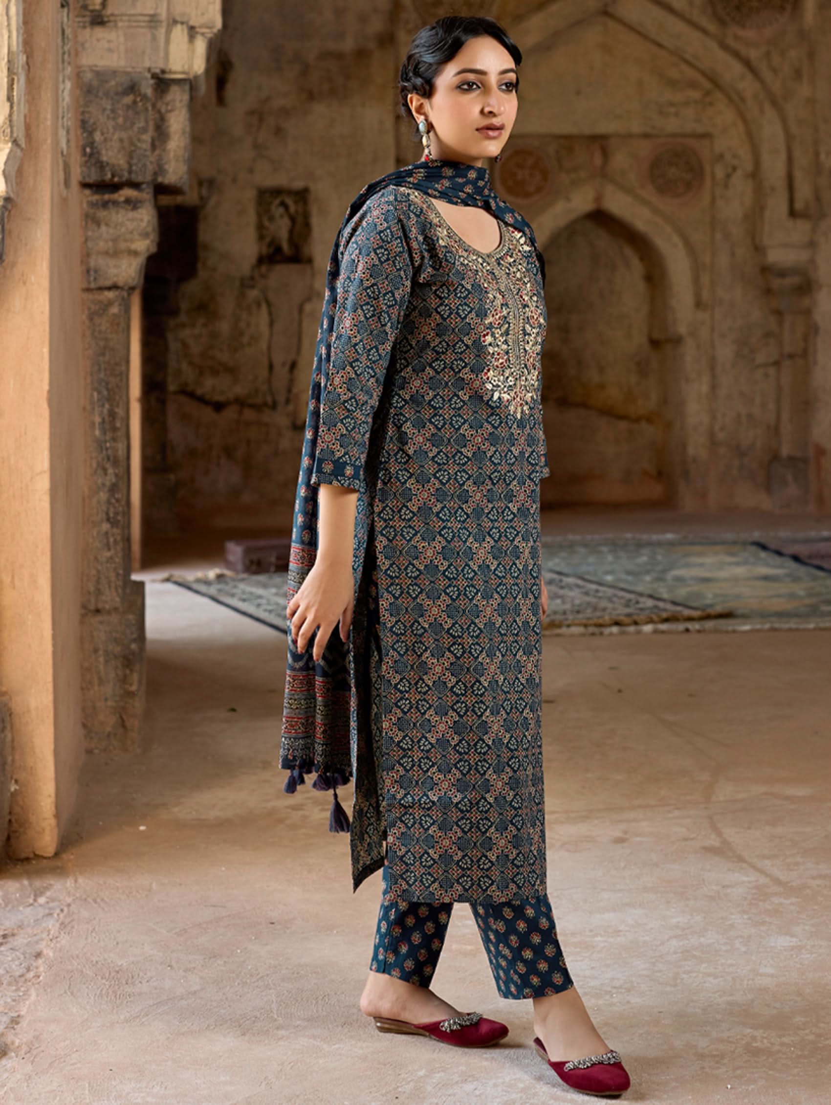 A woman wearing a green and white embroidered pure cotton suit set with three-quarter sleeves and side slits, including straight pants and a printed cotton dupatta.