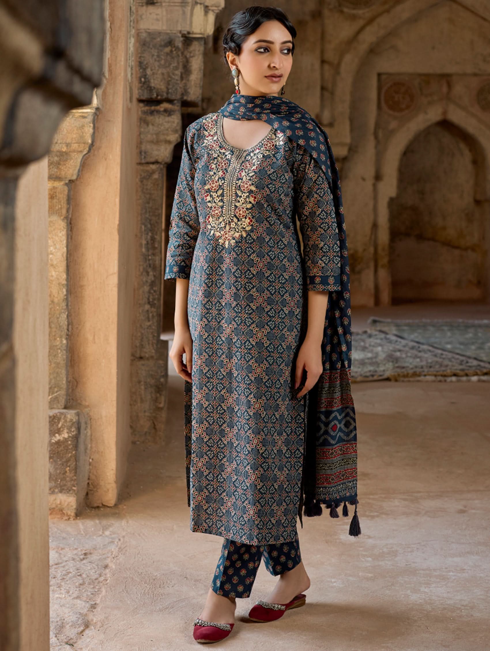 A woman wearing a green and white embroidered pure cotton suit set with three-quarter sleeves and side slits, including straight pants and a printed cotton dupatta.