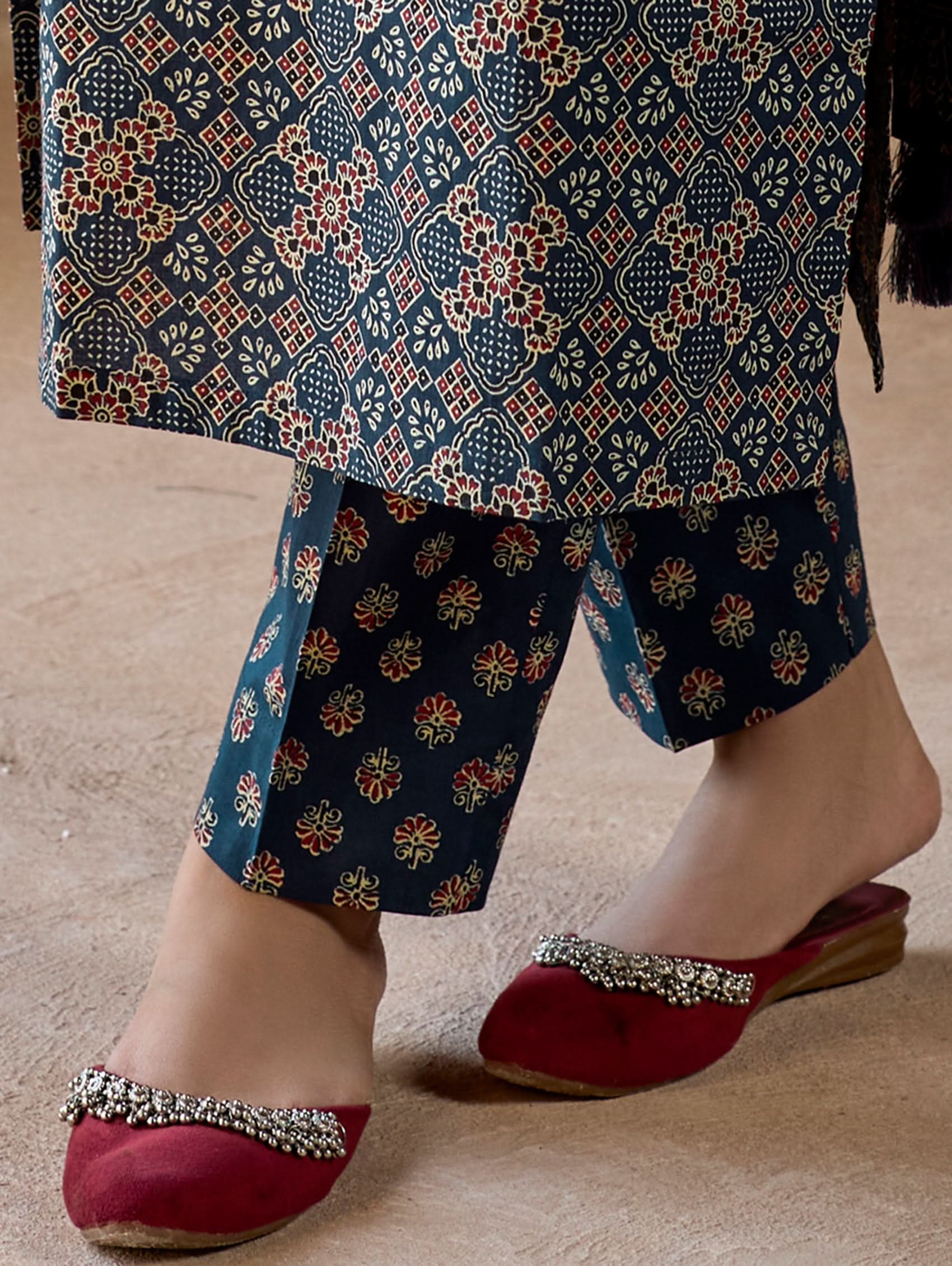 A woman wearing a green and white embroidered pure cotton suit set with three-quarter sleeves and side slits, including straight pants and a printed cotton dupatta.
