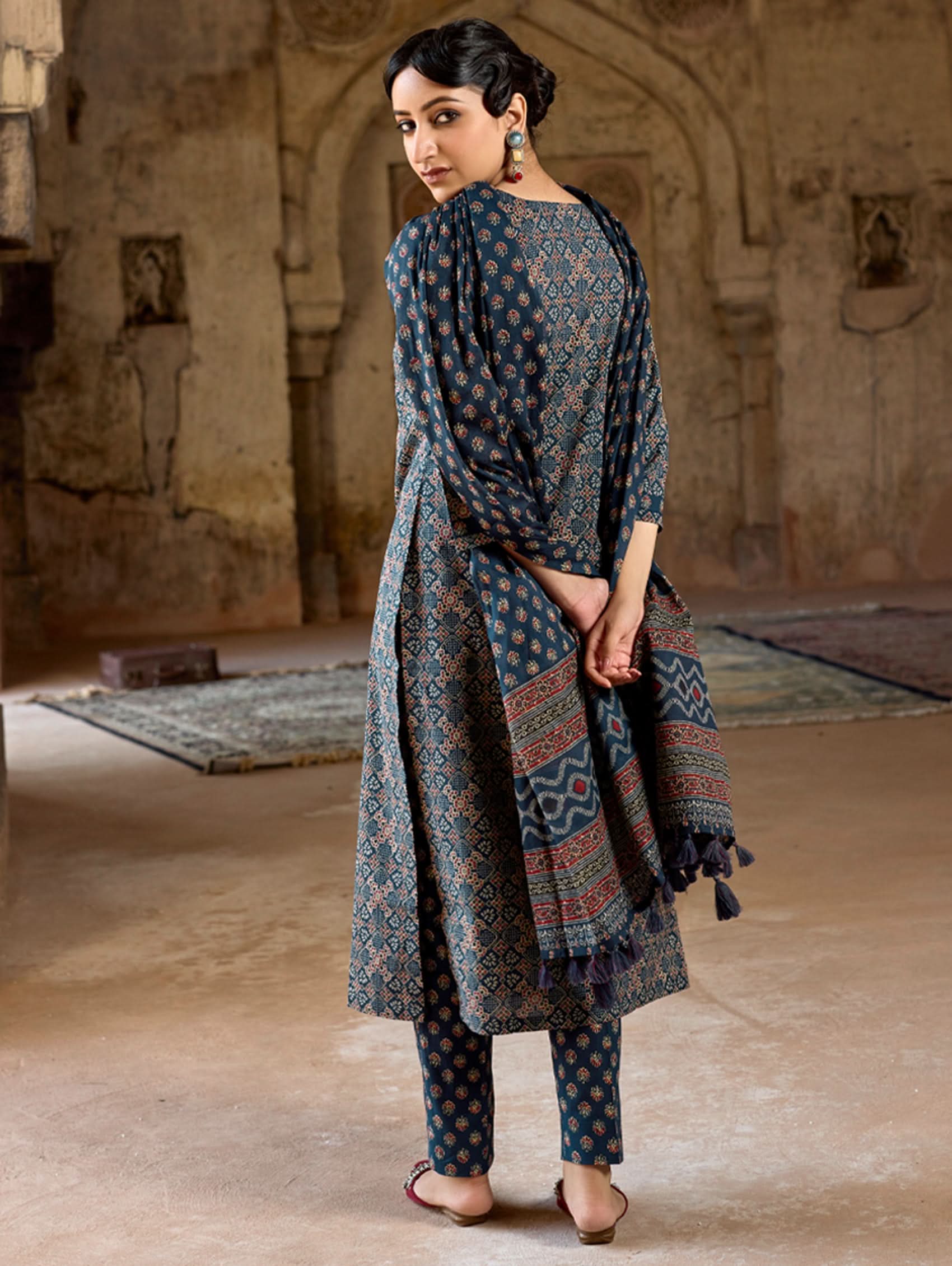 A woman wearing a green and white embroidered pure cotton suit set with three-quarter sleeves and side slits, including straight pants and a printed cotton dupatta.