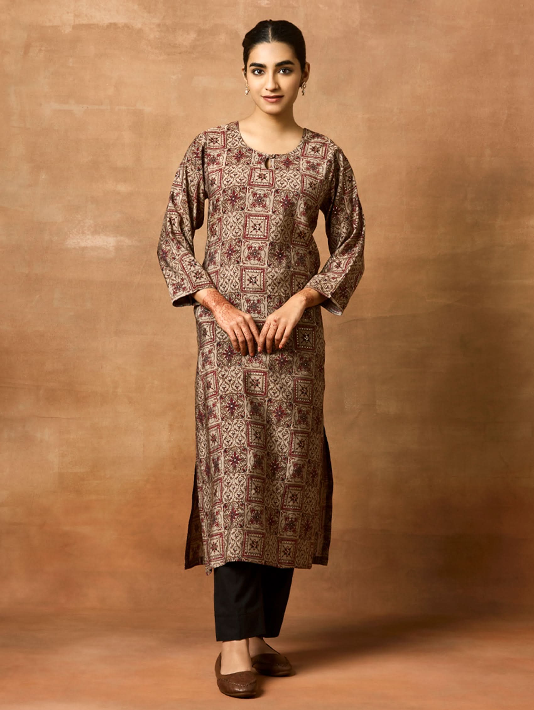 A woman plus size model wearing a brown printed viscose rayon kurta with Keyhole round neckline, three-fourth sleeves, and side slits.