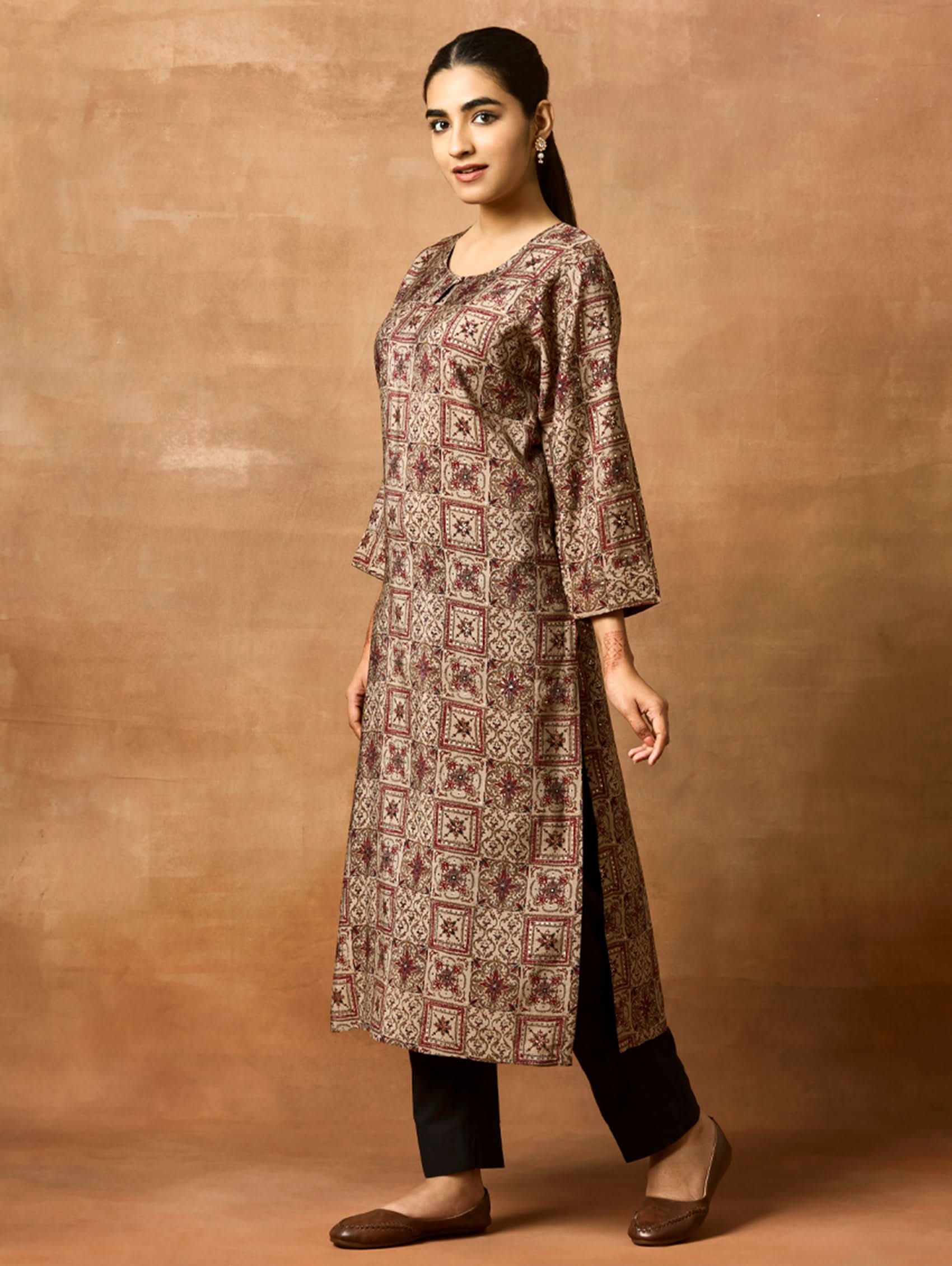 A woman plus size model wearing a brown printed viscose rayon kurta with Keyhole round neckline, three-fourth sleeves, and side slits.