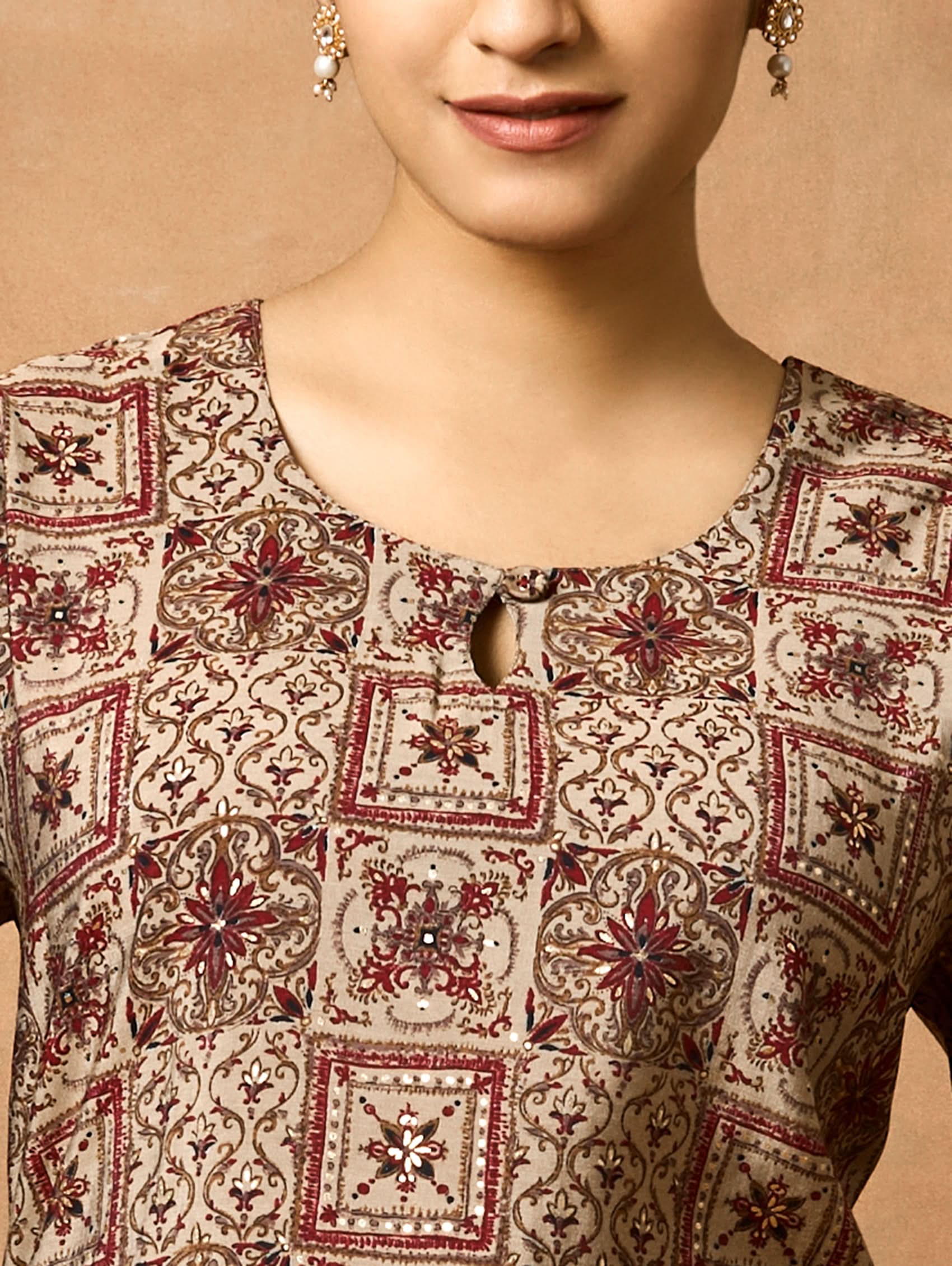 A woman plus size model wearing a brown printed viscose rayon kurta with Keyhole round neckline, three-fourth sleeves, and side slits.