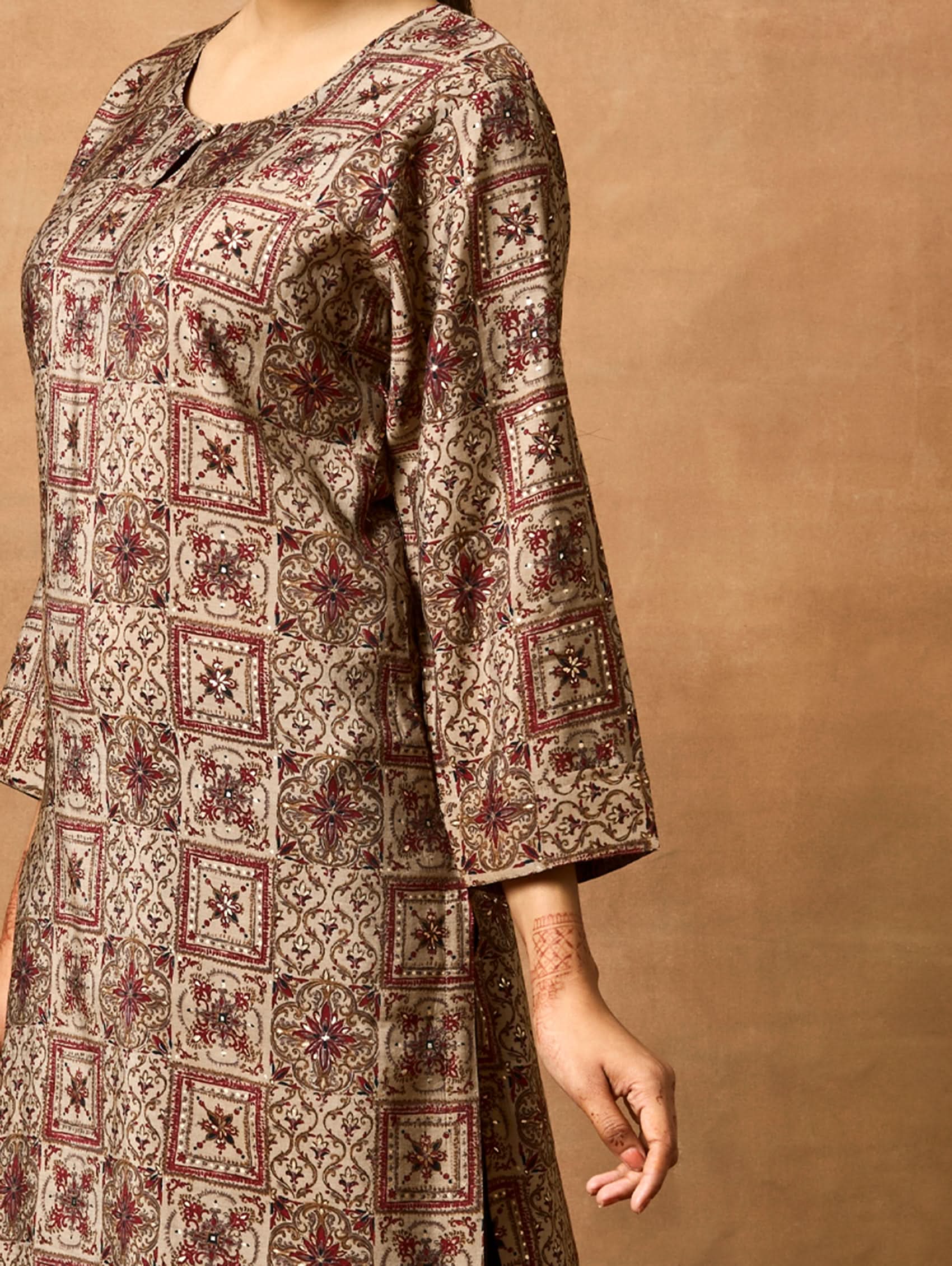 A woman plus size model wearing a brown printed viscose rayon kurta with Keyhole round neckline, three-fourth sleeves, and side slits.