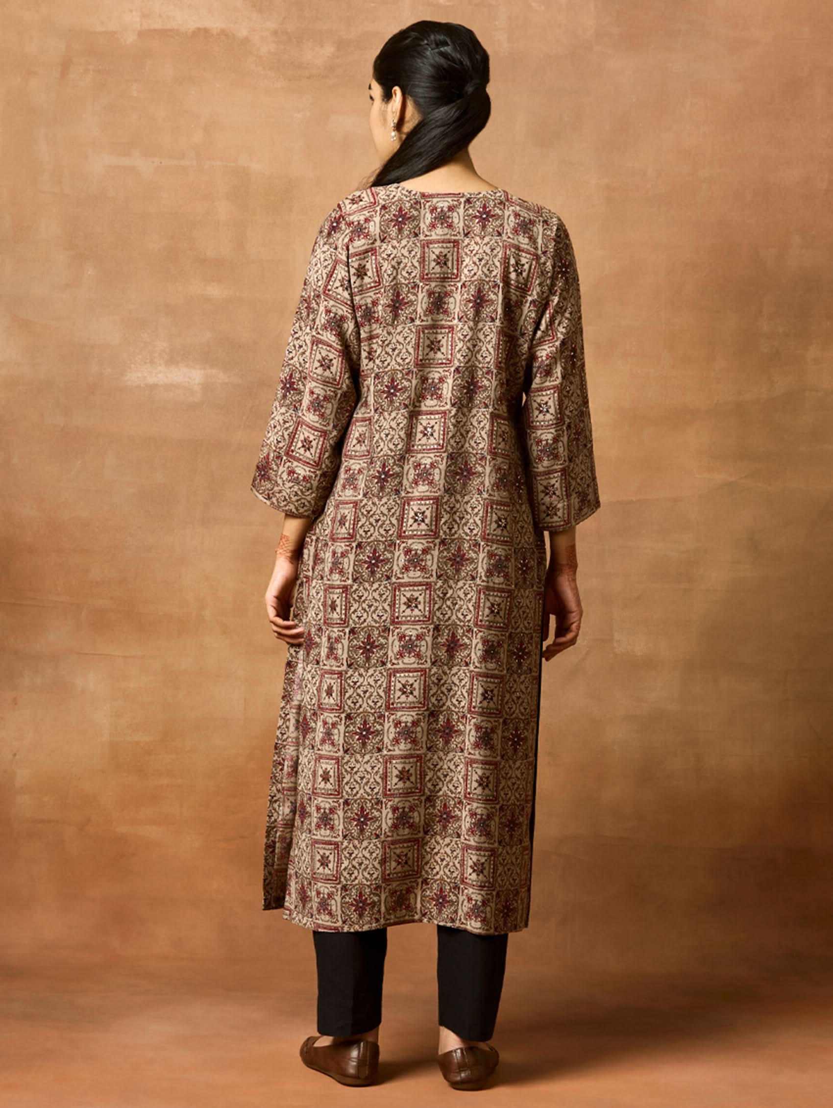 A woman plus size model wearing a brown printed viscose rayon kurta with Keyhole round neckline, three-fourth sleeves, and side slits.