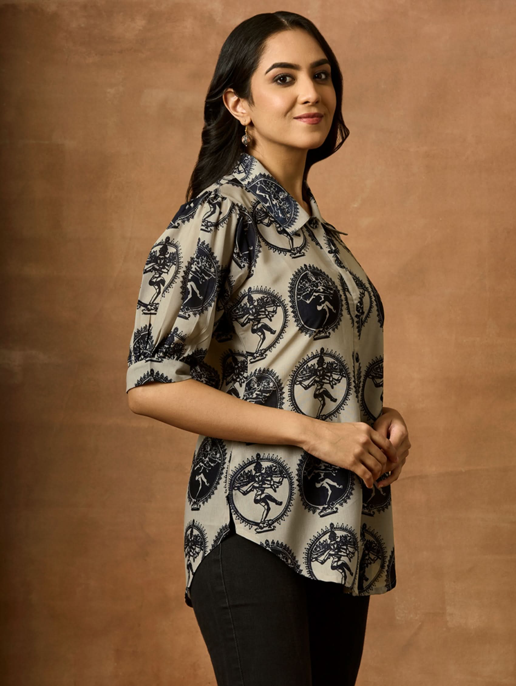 A woman wearing a beige and navy printed summer cool viscose tunic with a revere collar and half-length sleeves.