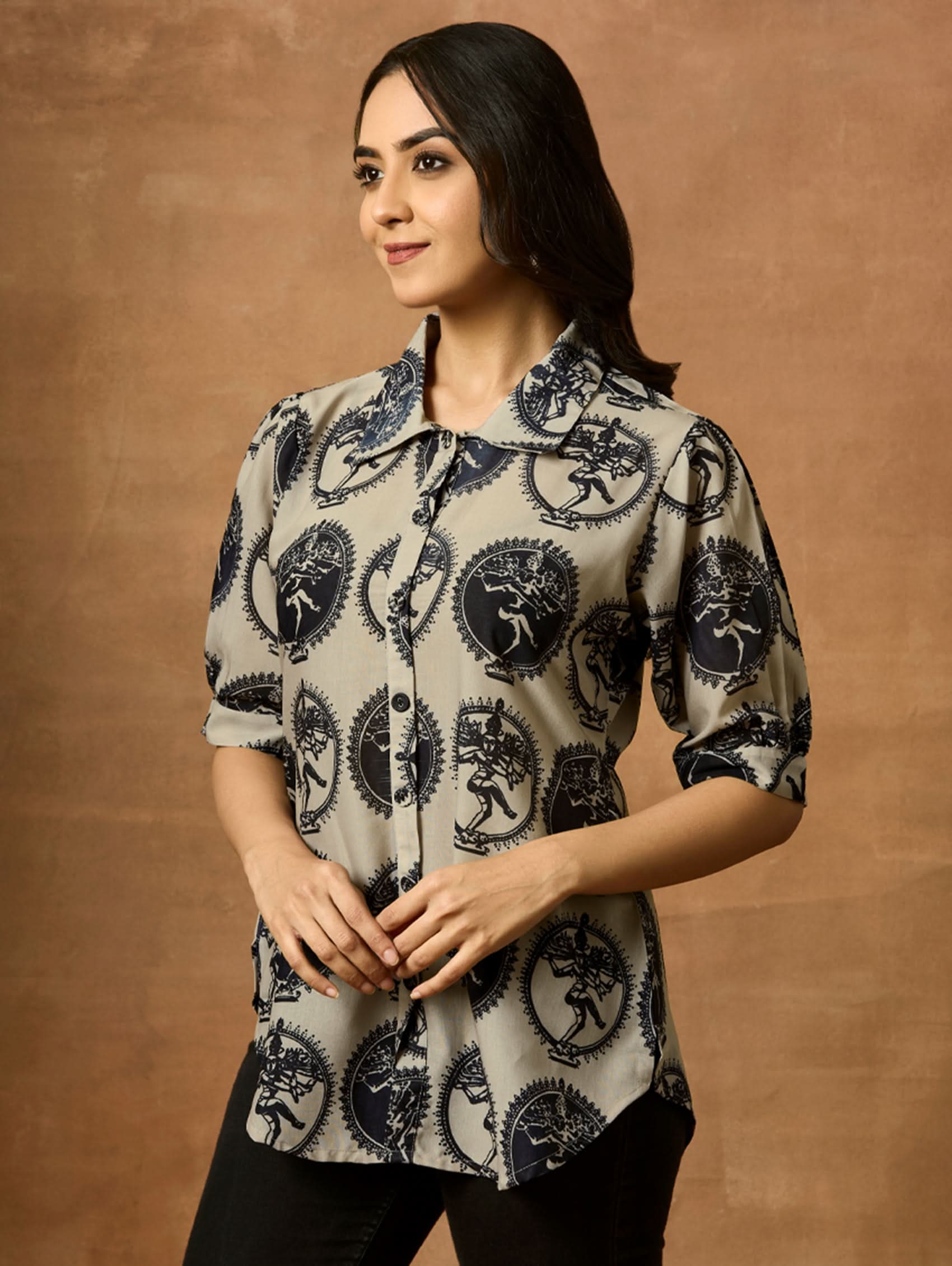 A woman wearing a beige and navy printed summer cool viscose tunic with a revere collar and half-length sleeves.