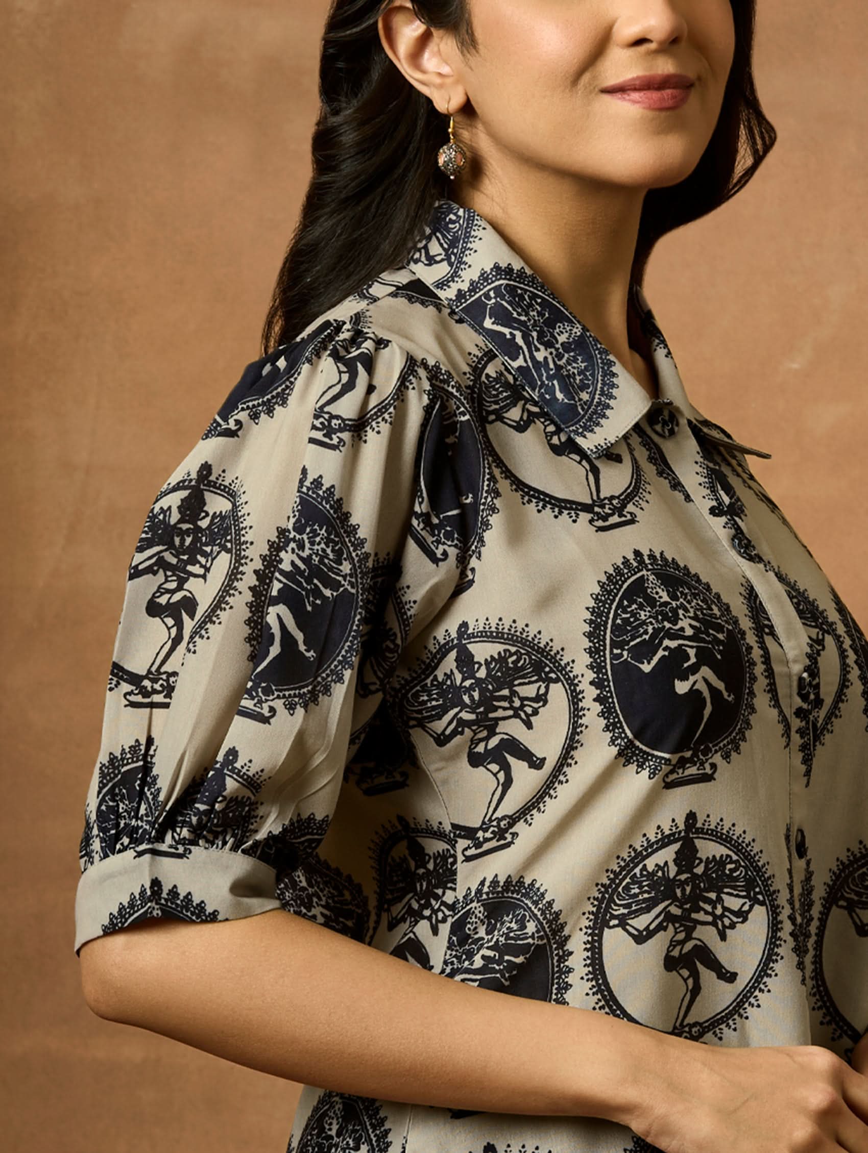 A woman wearing a beige and navy printed summer cool viscose tunic with a revere collar and half-length sleeves.