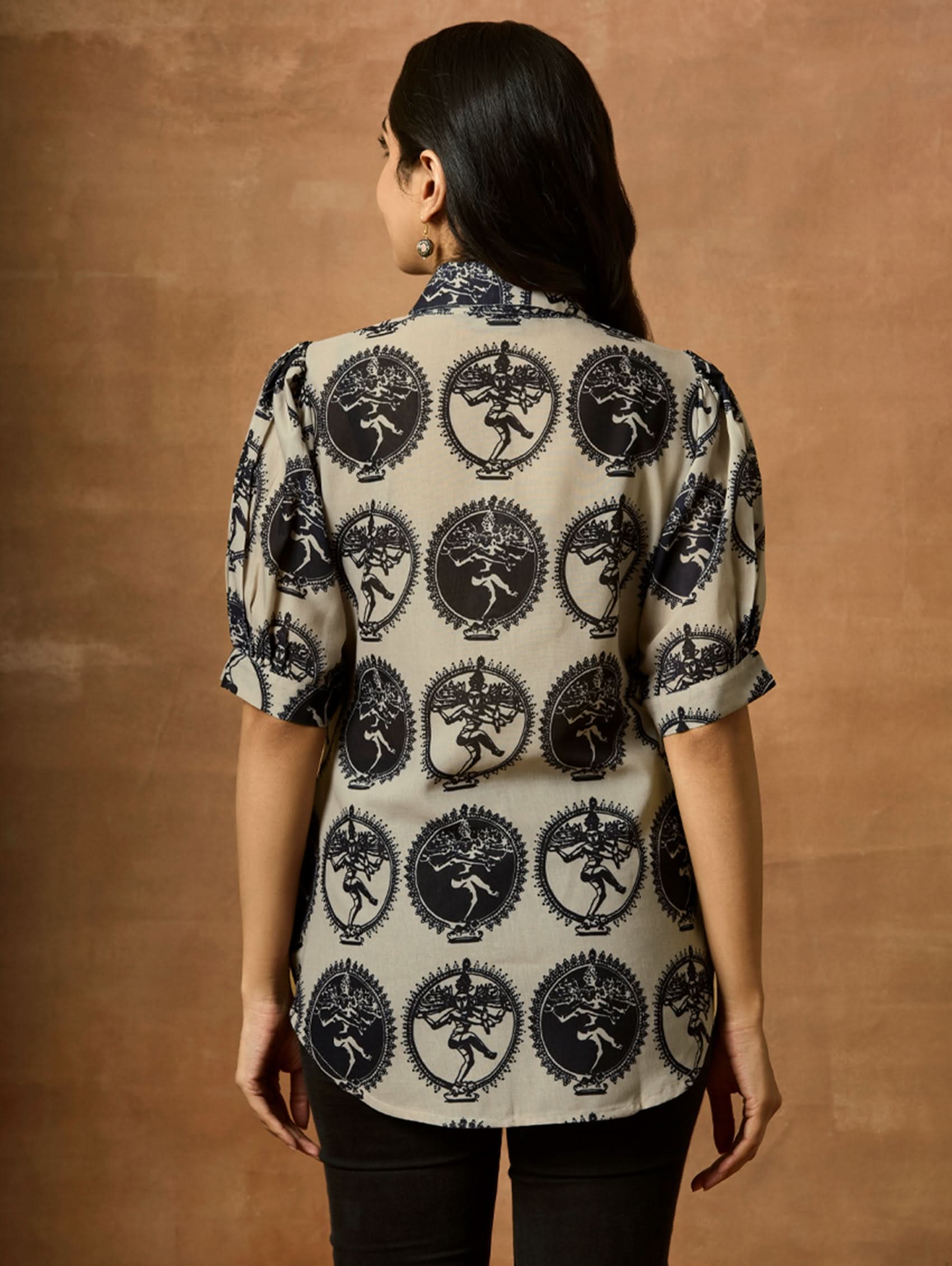 A woman wearing a beige and navy printed summer cool viscose tunic with a revere collar and half-length sleeves.