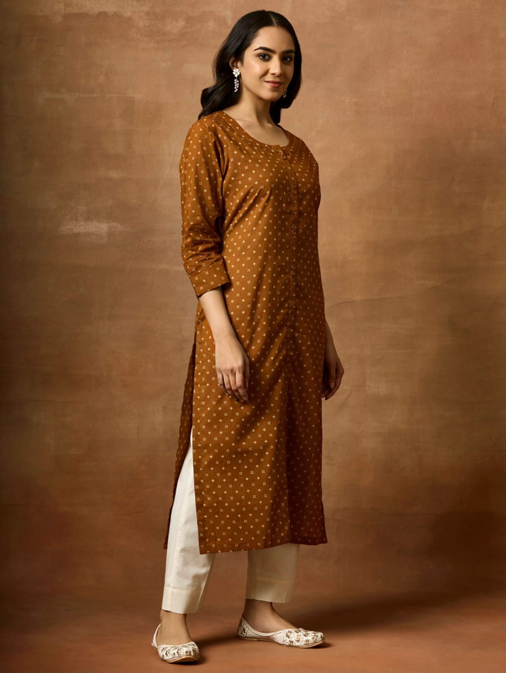 Woman wearing a brown polka dot kurta against a brown background