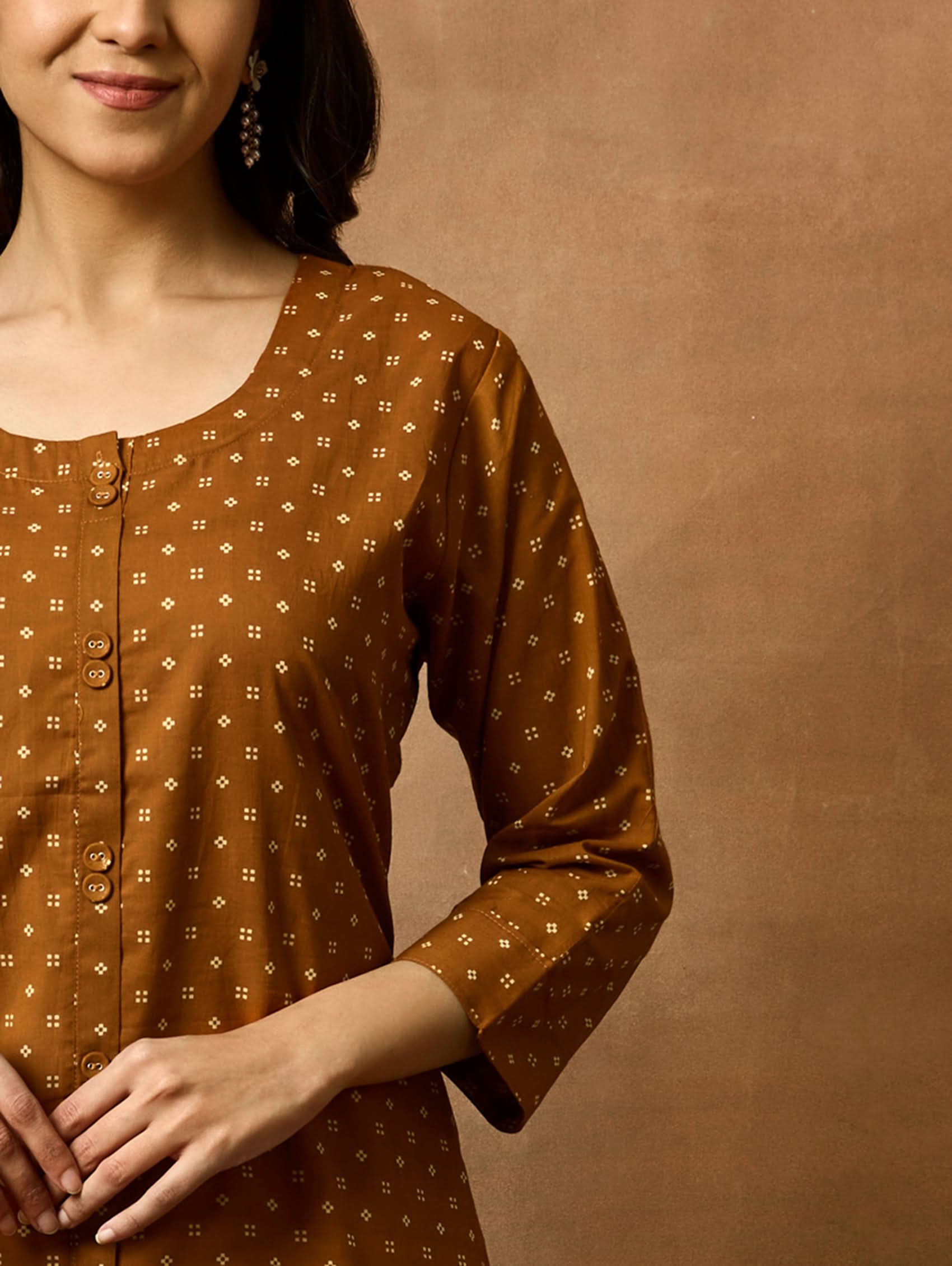 Woman wearing a brown patterned top against a brown background