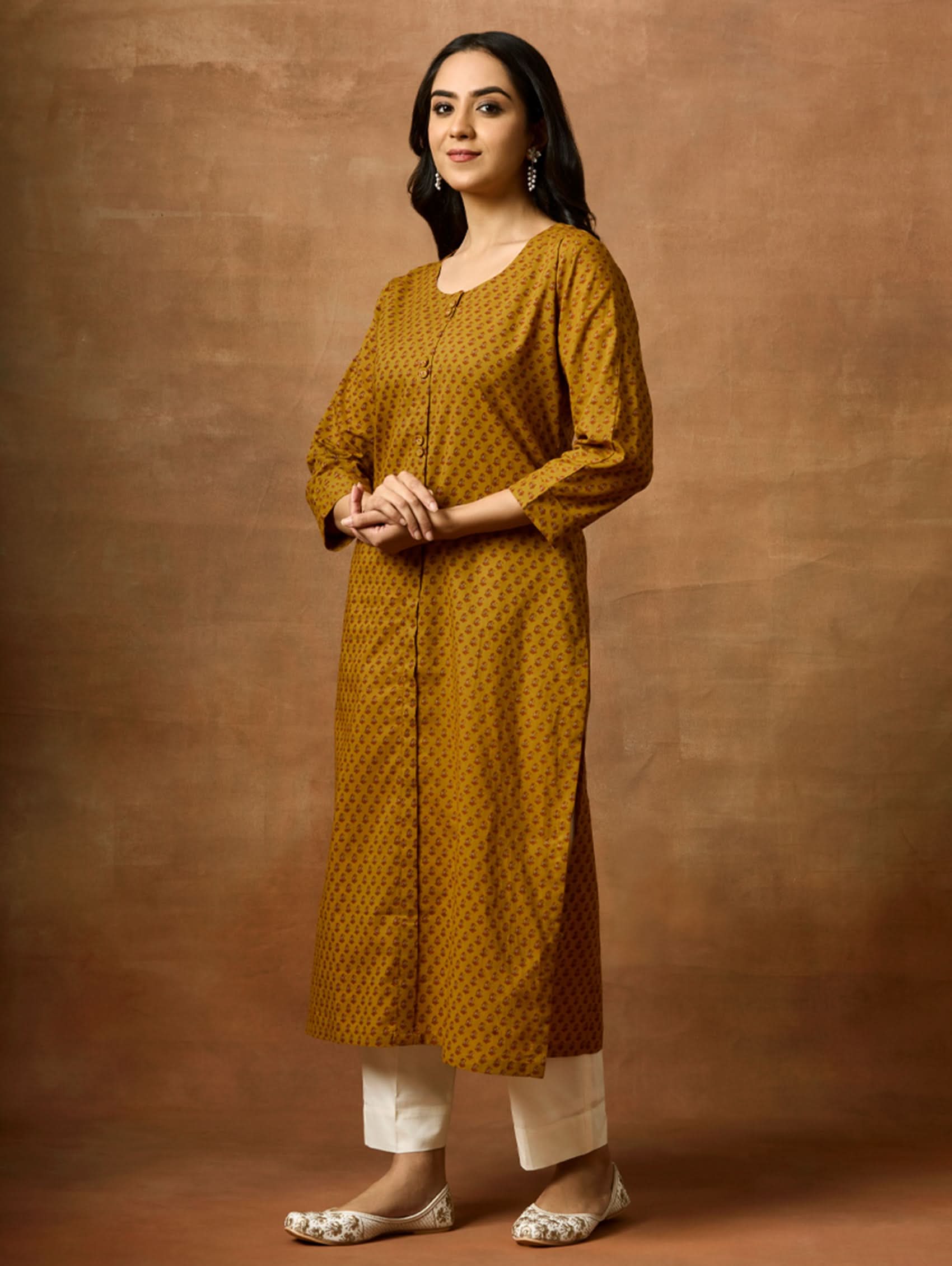 Woman wearing a mustard yellow patterned kurta against a brown background