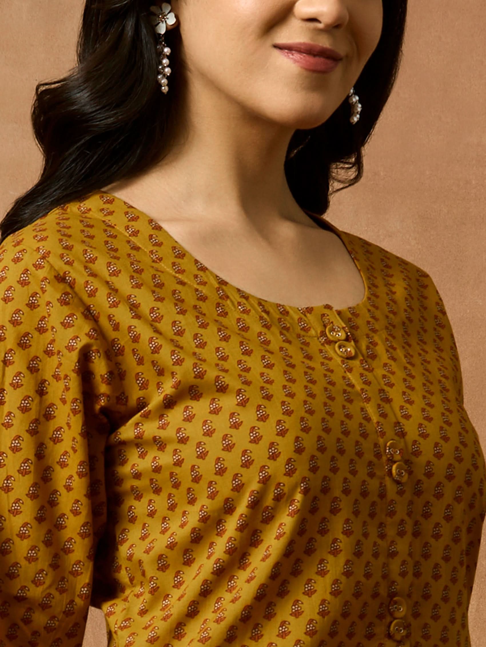 Woman wearing a yellow patterned blouse with a brown background