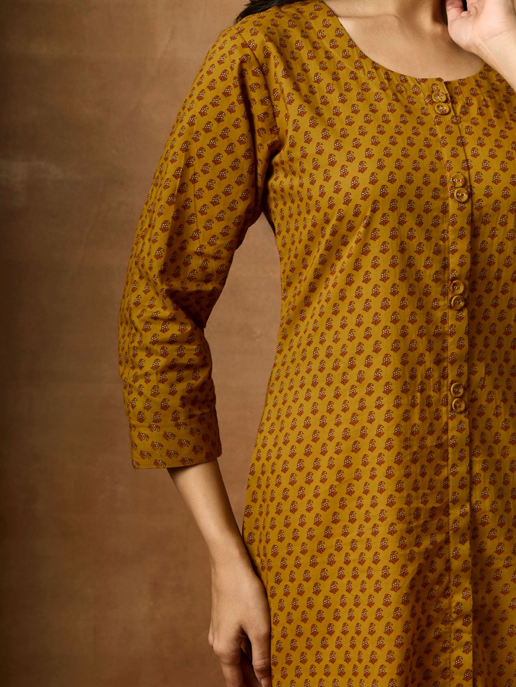 Yellow patterned dress against a brown background
