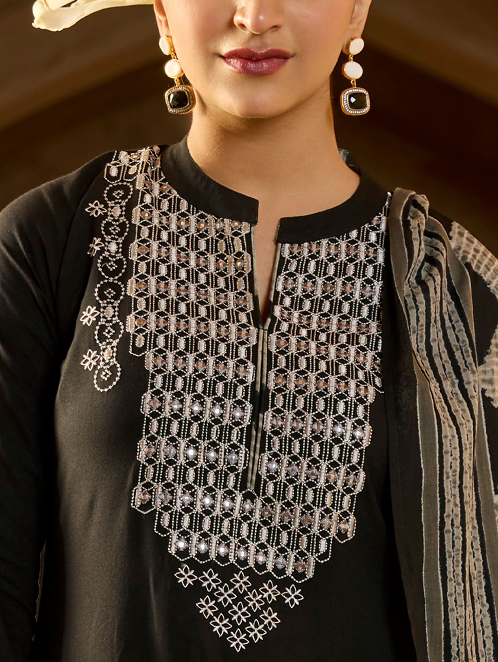 A woman wearing a black viscose rayon suit set with embroidery on the kurta, consisting of a kurta, pants, and a printed dupatta.