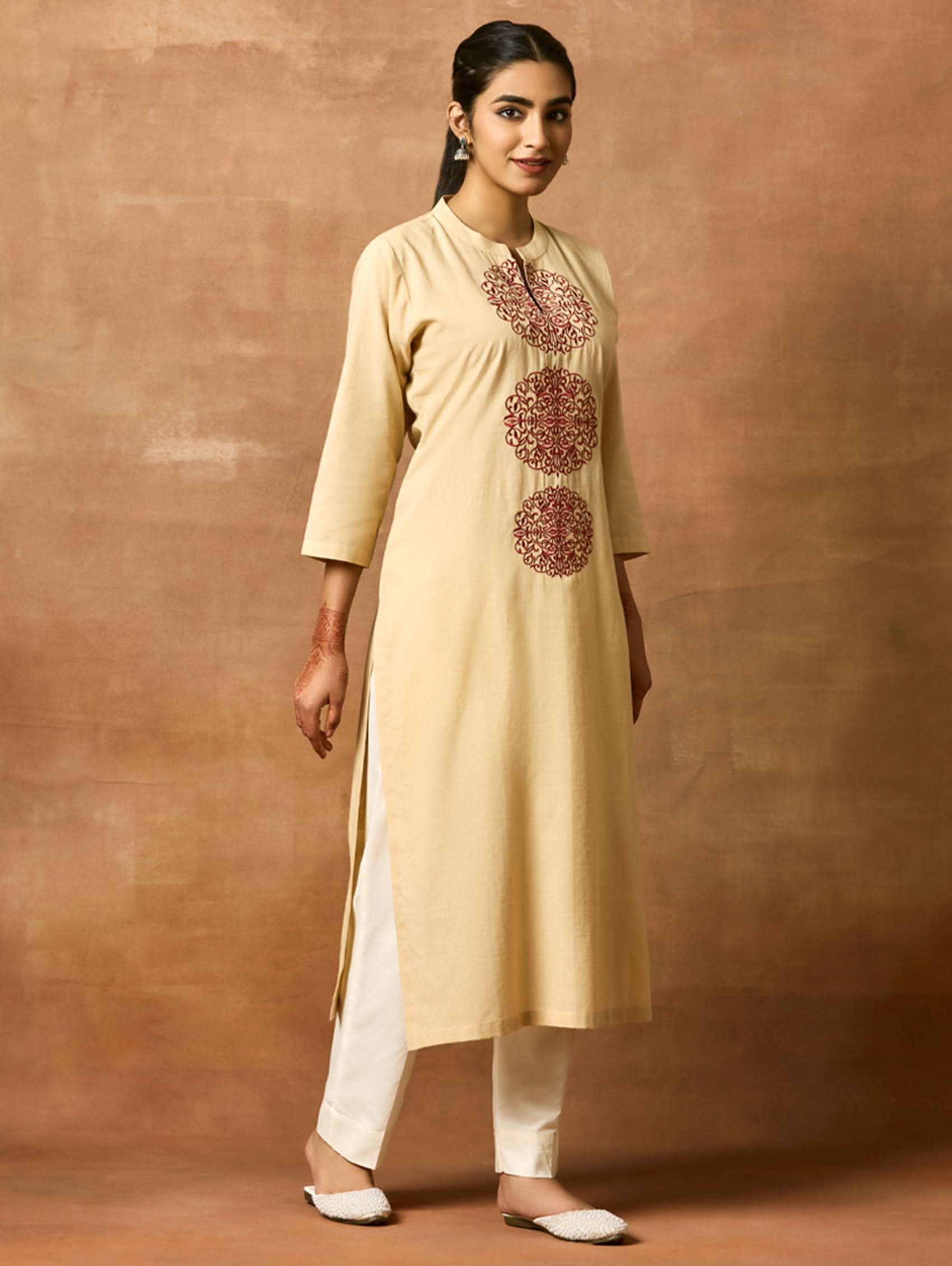 A woman plus-size model wearing a beige kurta with ban collar and three-fourth sleeves, featuring computerised thread embroidery.