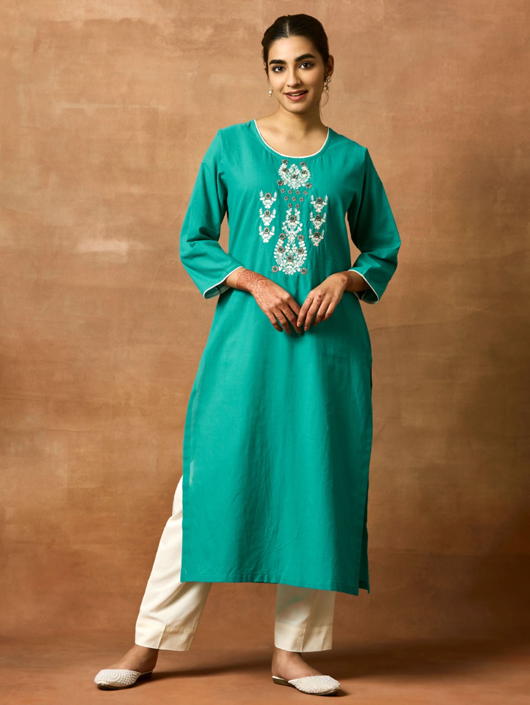 A woman plus-size model wearing a green pure cotton kurta with round neckline, three-fourth sleeves, and side slits. The kurta is embellished with computerised thread embroidery.