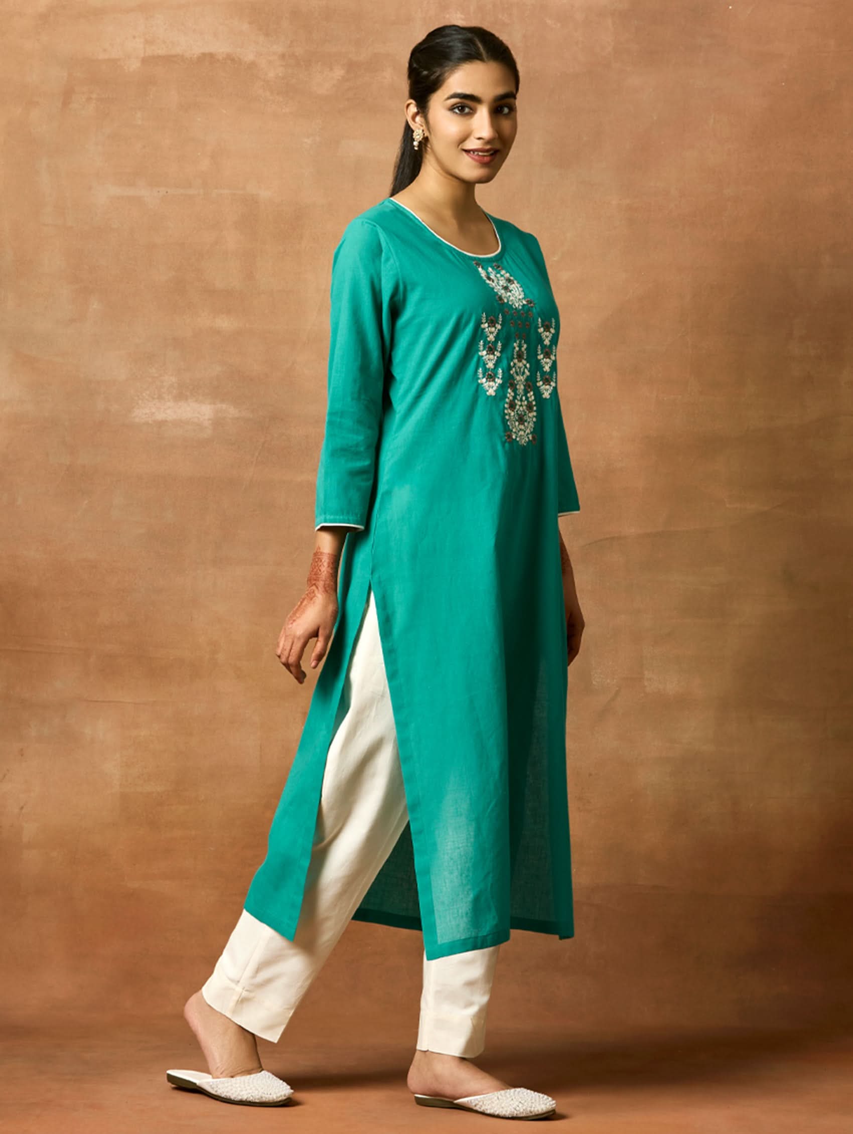 A woman plus-size model wearing a green pure cotton kurta with round neckline, three-fourth sleeves, and side slits. The kurta is embellished with computerised thread embroidery.