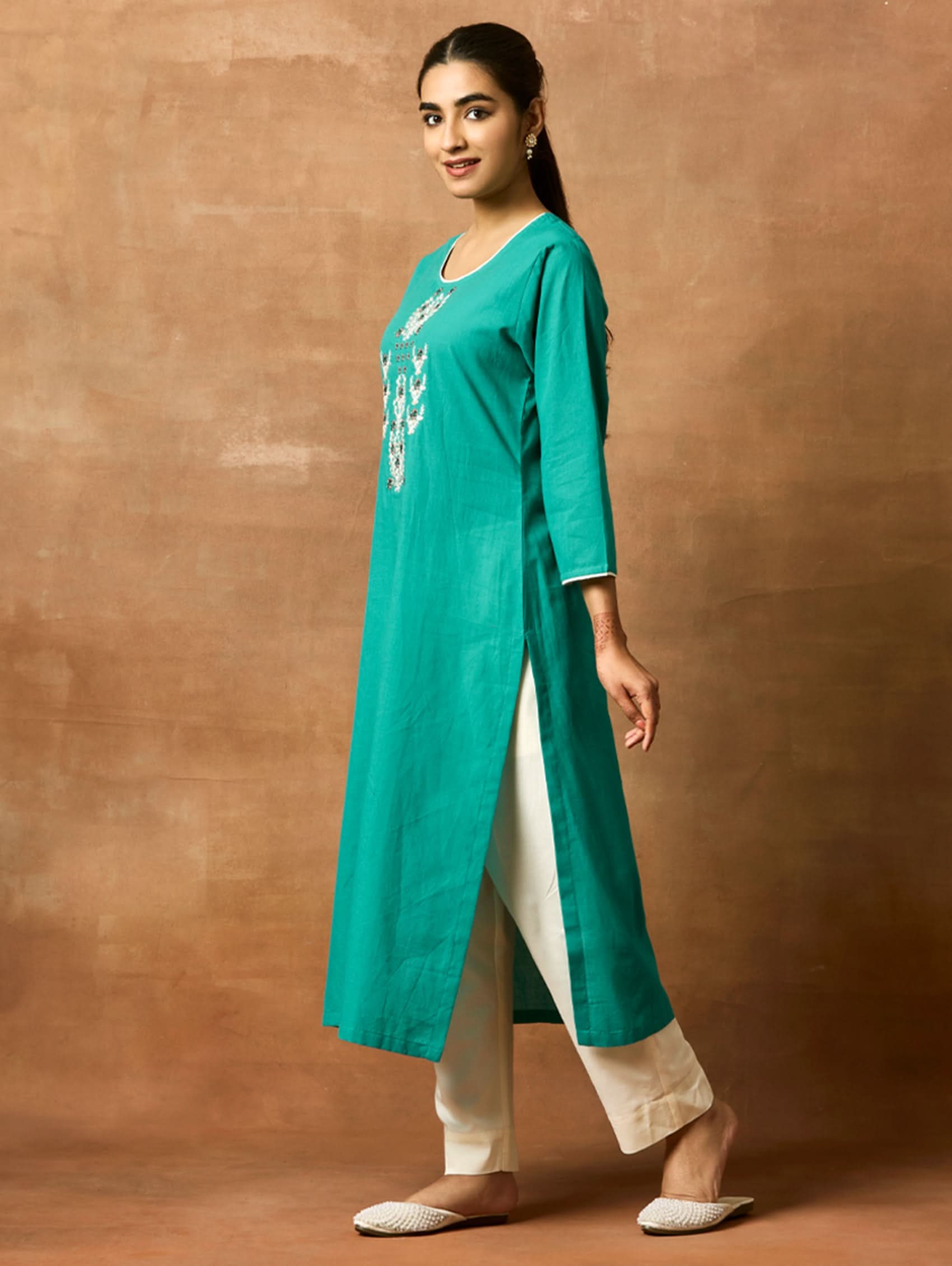 A woman plus-size model wearing a green pure cotton kurta with round neckline, three-fourth sleeves, and side slits. The kurta is embellished with computerised thread embroidery.