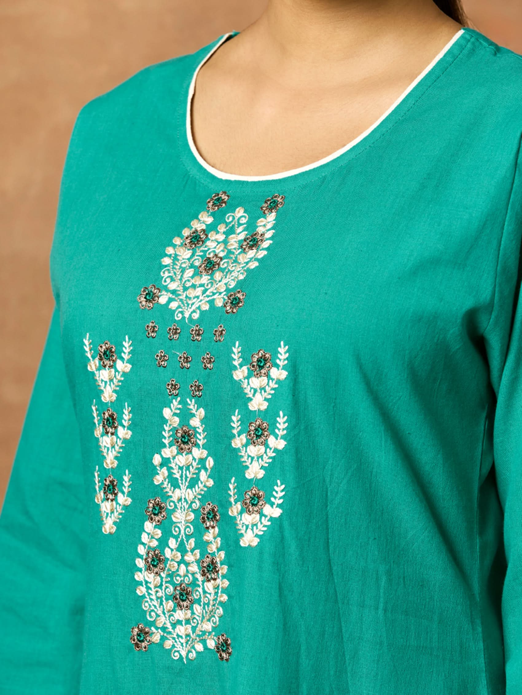 A woman plus-size model wearing a green pure cotton kurta with round neckline, three-fourth sleeves, and side slits. The kurta is embellished with computerised thread embroidery.