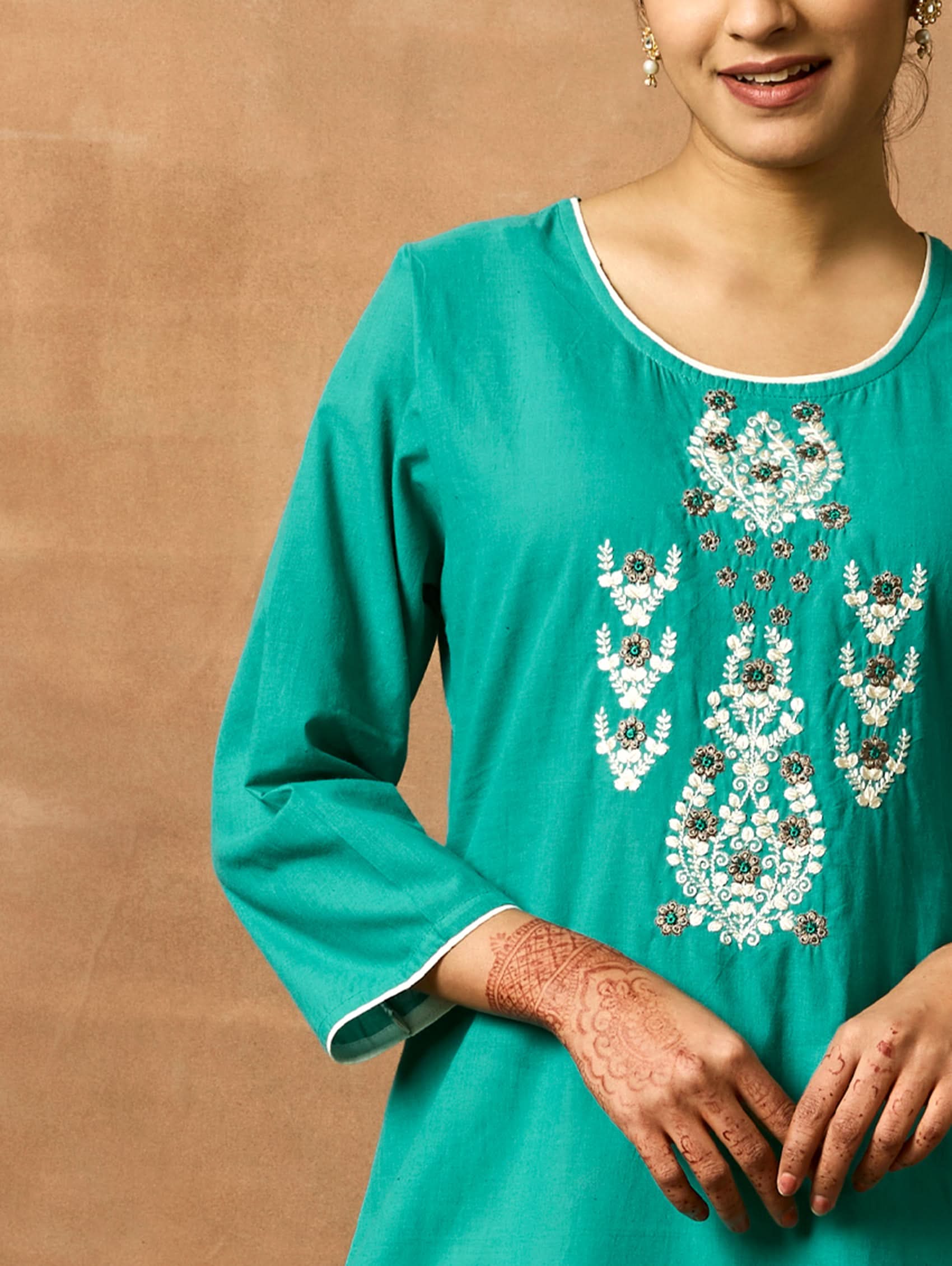 A woman plus-size model wearing a green pure cotton kurta with round neckline, three-fourth sleeves, and side slits. The kurta is embellished with computerised thread embroidery.