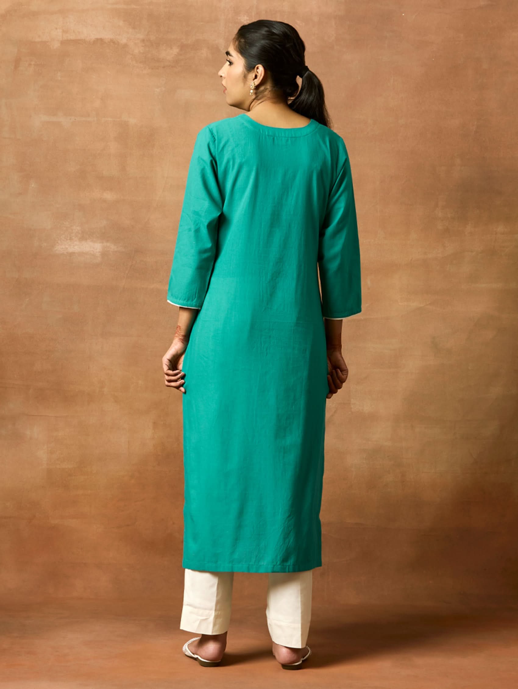 A woman plus-size model wearing a green pure cotton kurta with round neckline, three-fourth sleeves, and side slits. The kurta is embellished with computerised thread embroidery.