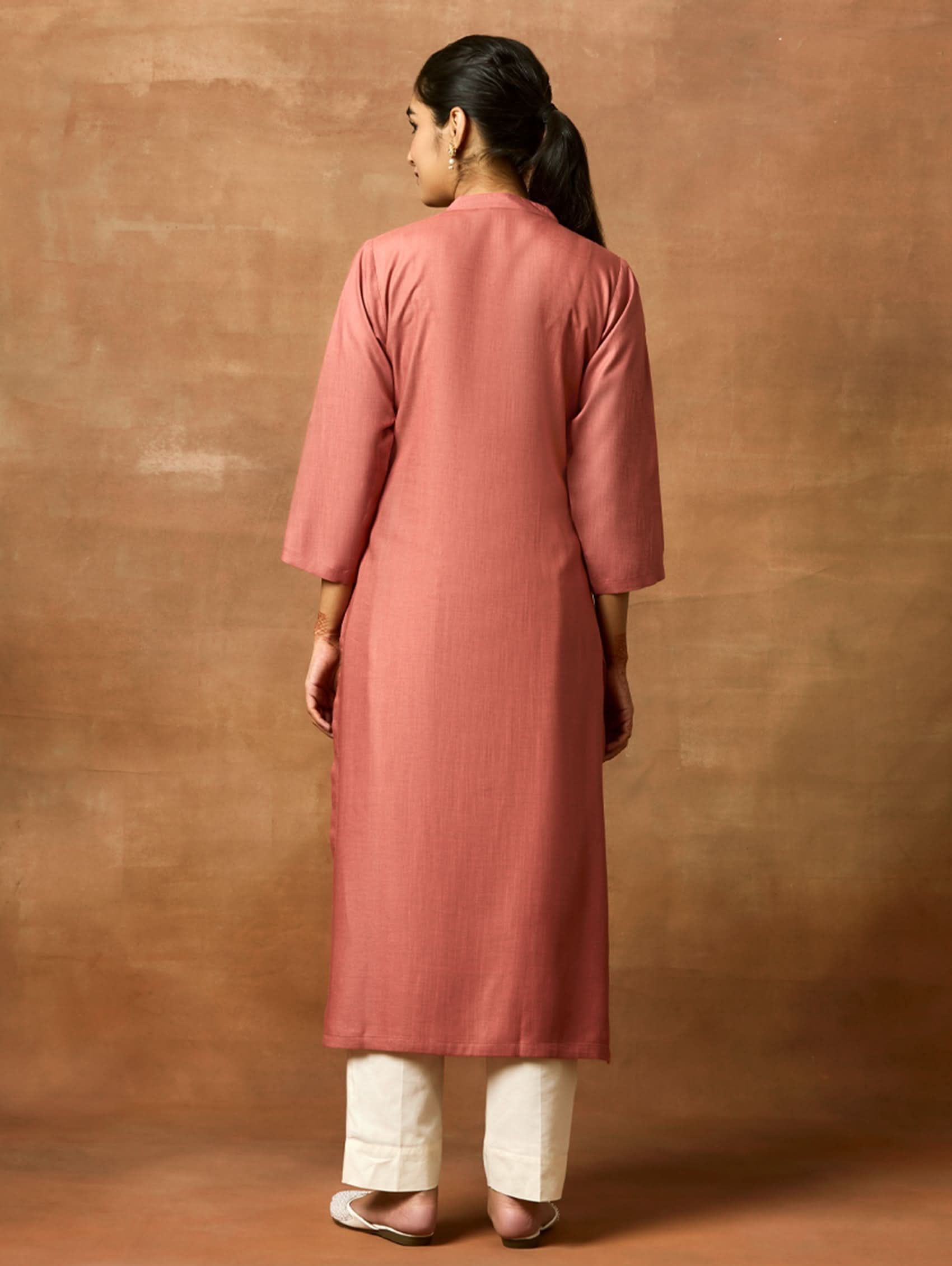Person wearing a pink kurta against a brown background