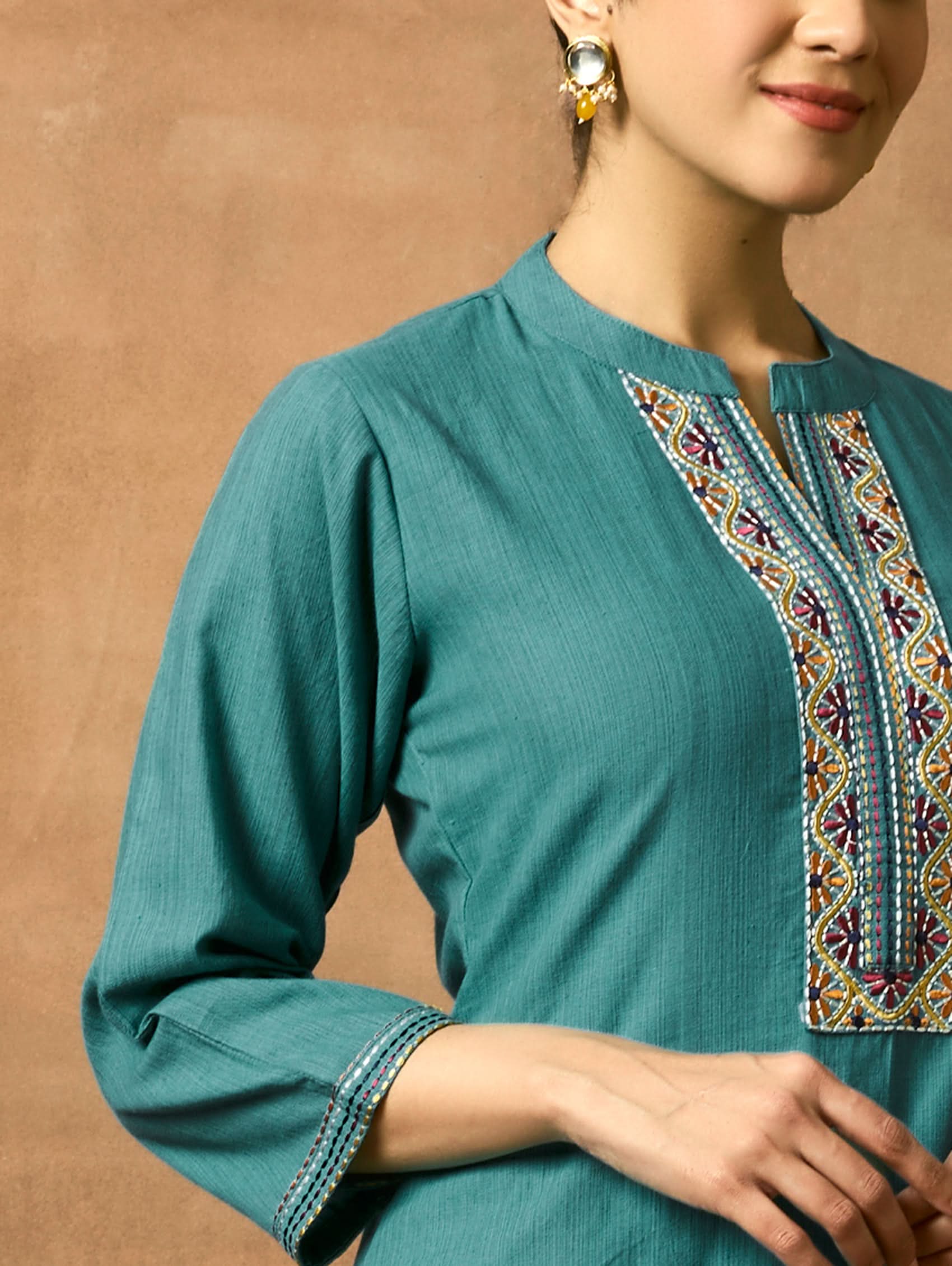 Teal kurta with colorful embroidery on a plain background