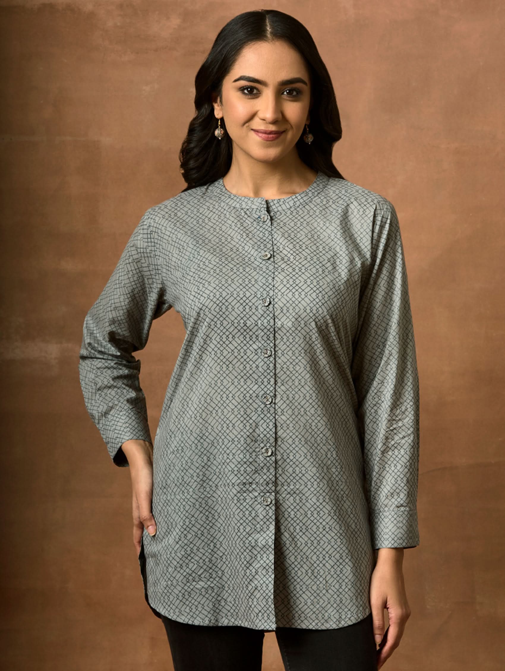 A woman wearing a gray and white printed pure cotton short kurti with a mandarin collar, full sleeves, and side slits.