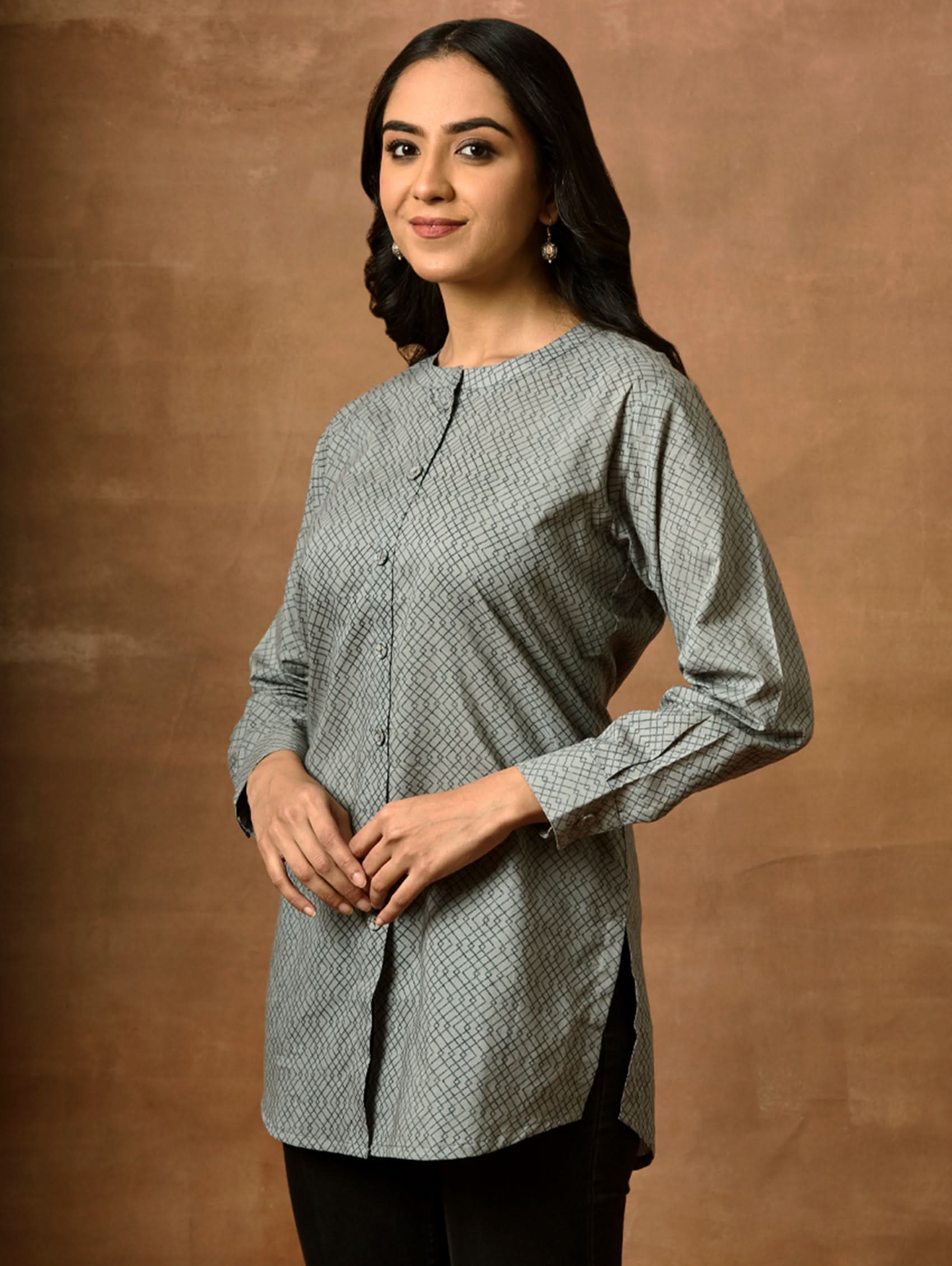 A woman wearing a gray and white printed pure cotton short kurti with a mandarin collar, full sleeves, and side slits.