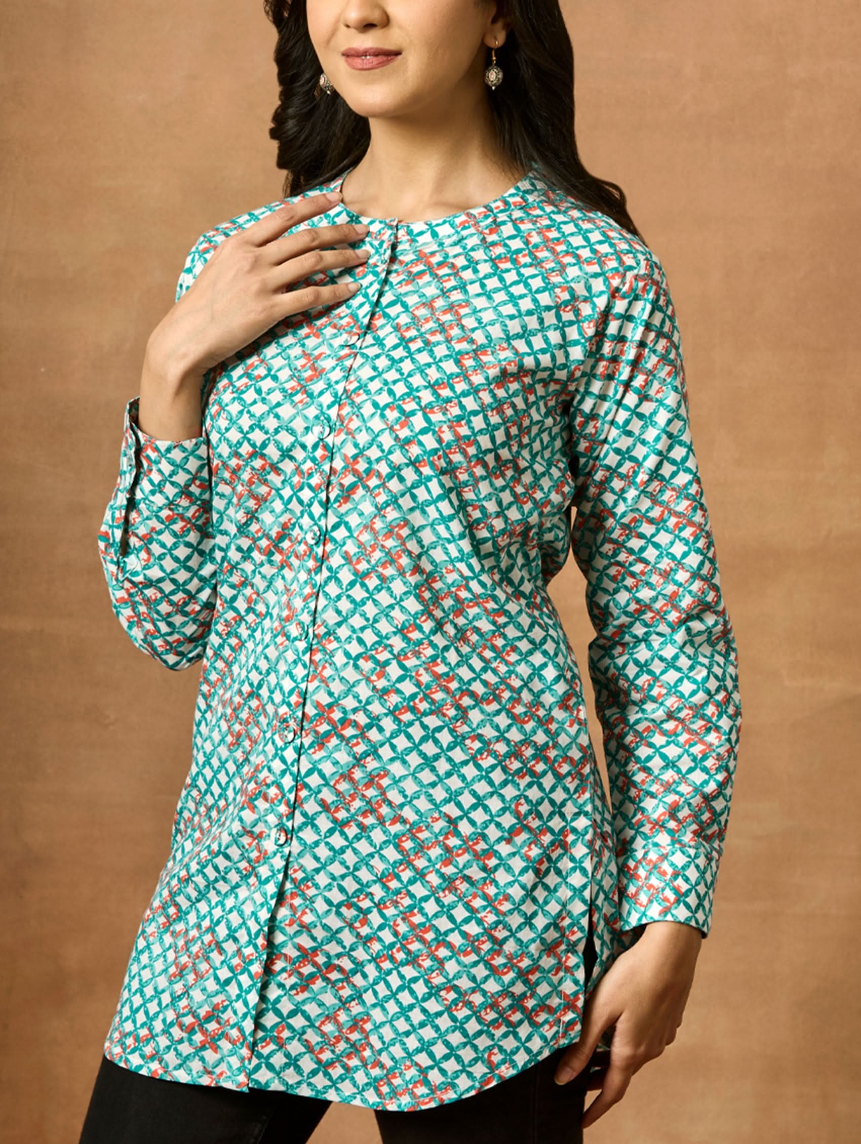 A woman wearing a green and red printed pure cotton short kurti with a mandarin collar and full sleeves.