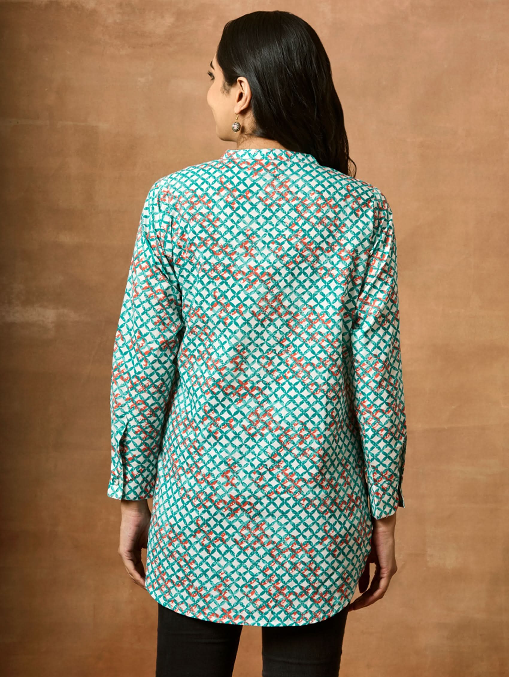 A woman wearing a green and red printed pure cotton short kurti with a mandarin collar and full sleeves.