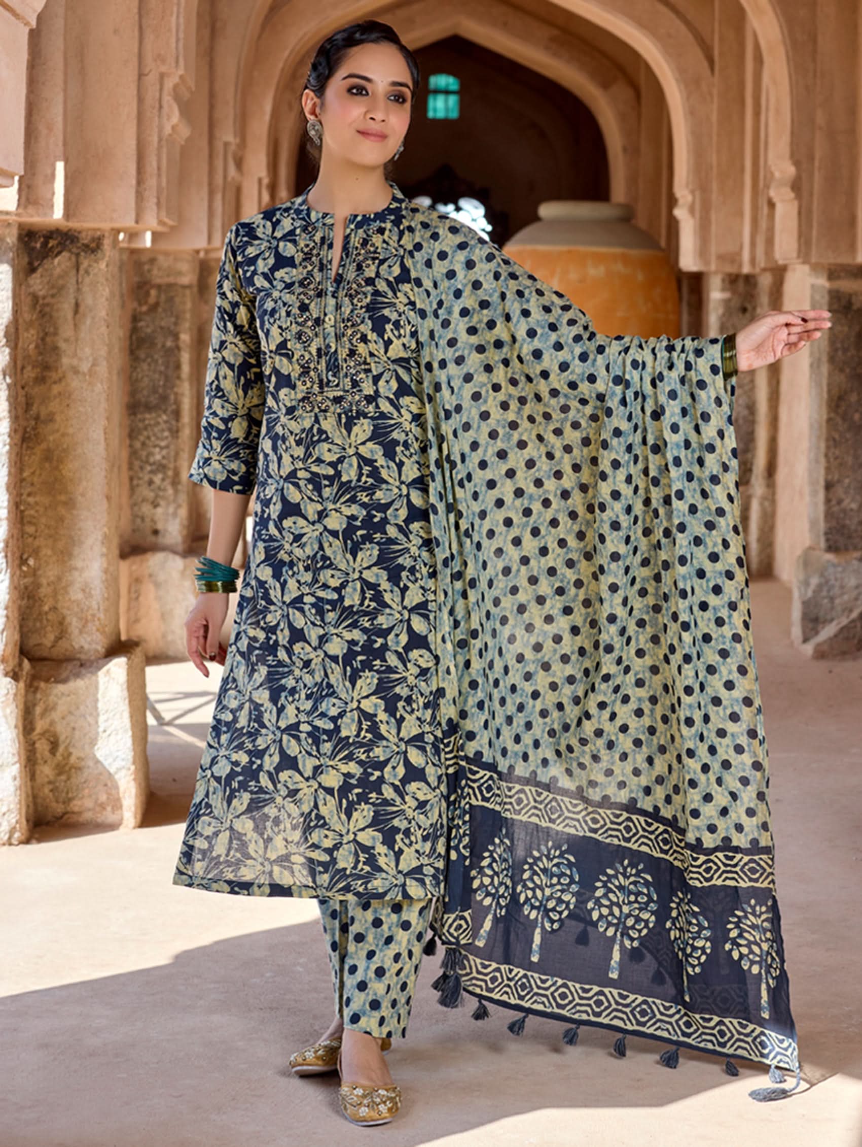 A woman wearing a traditional suit set with embroidered pure cotton kurta, pants, and a printed cotton mul dupatta.
