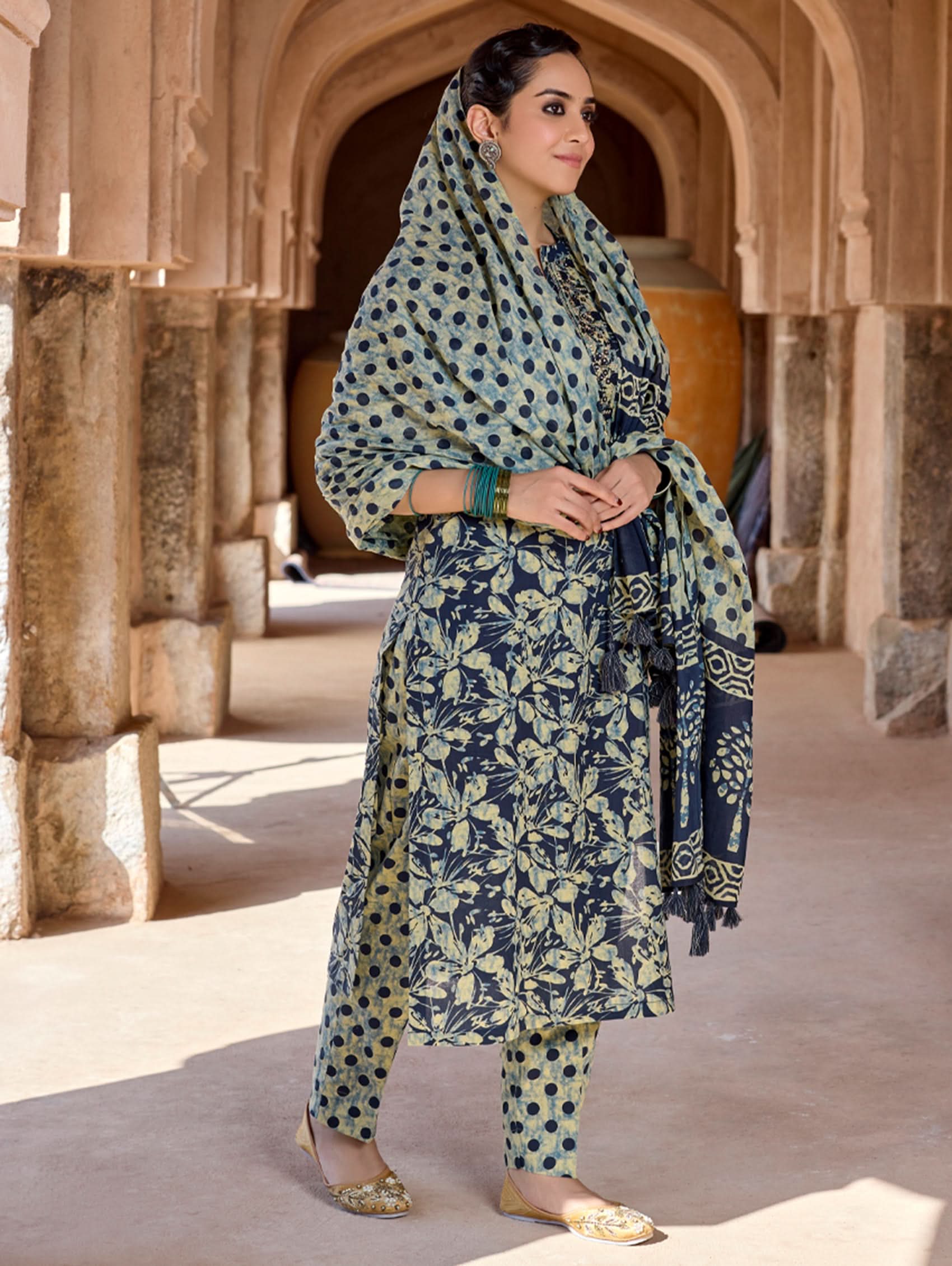 A woman wearing a traditional suit set with embroidered pure cotton kurta, pants, and a printed cotton mul dupatta.