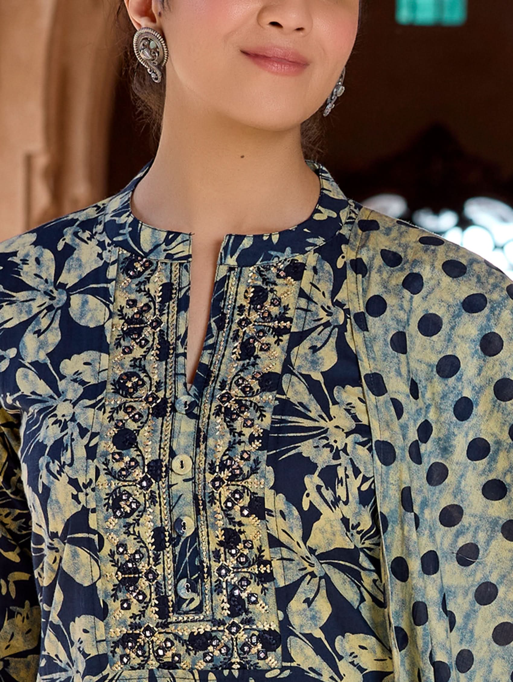 A woman wearing a traditional suit set with embroidered pure cotton kurta, pants, and a printed cotton mul dupatta.