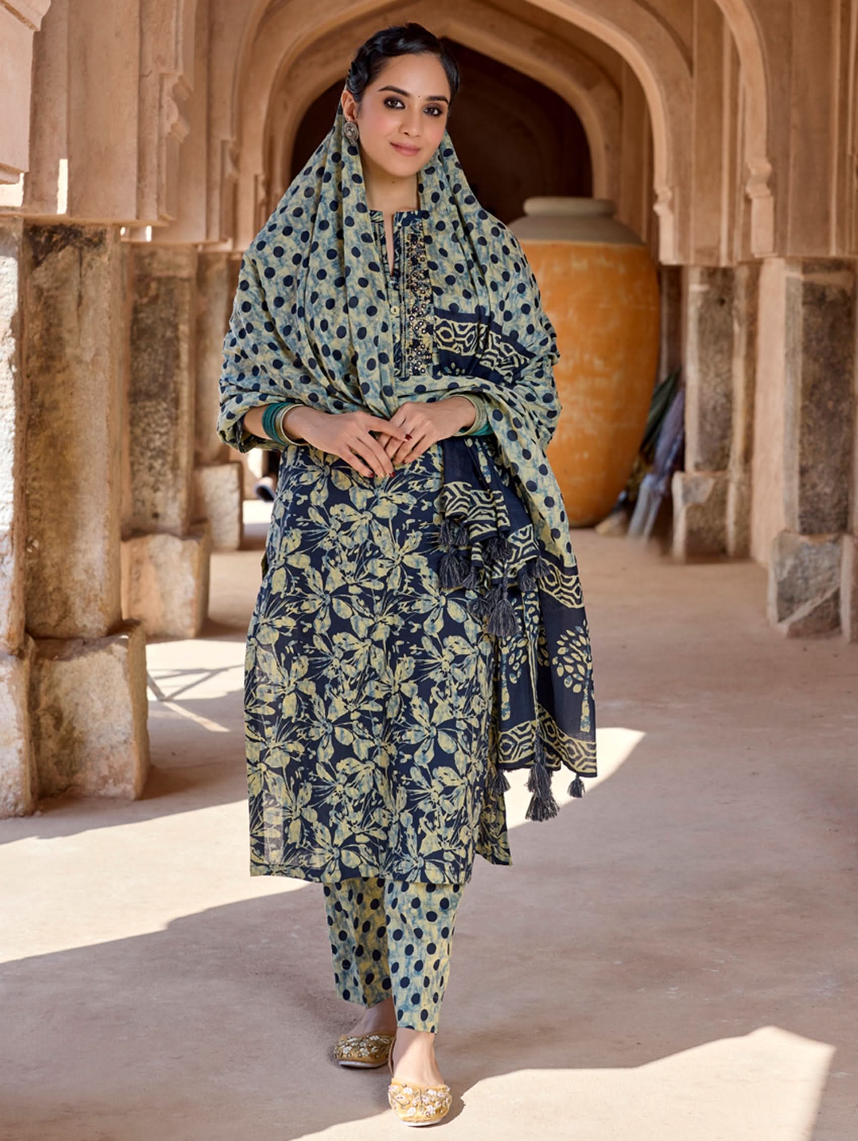 A woman wearing a traditional suit set with embroidered pure cotton kurta, pants, and a printed cotton mul dupatta.