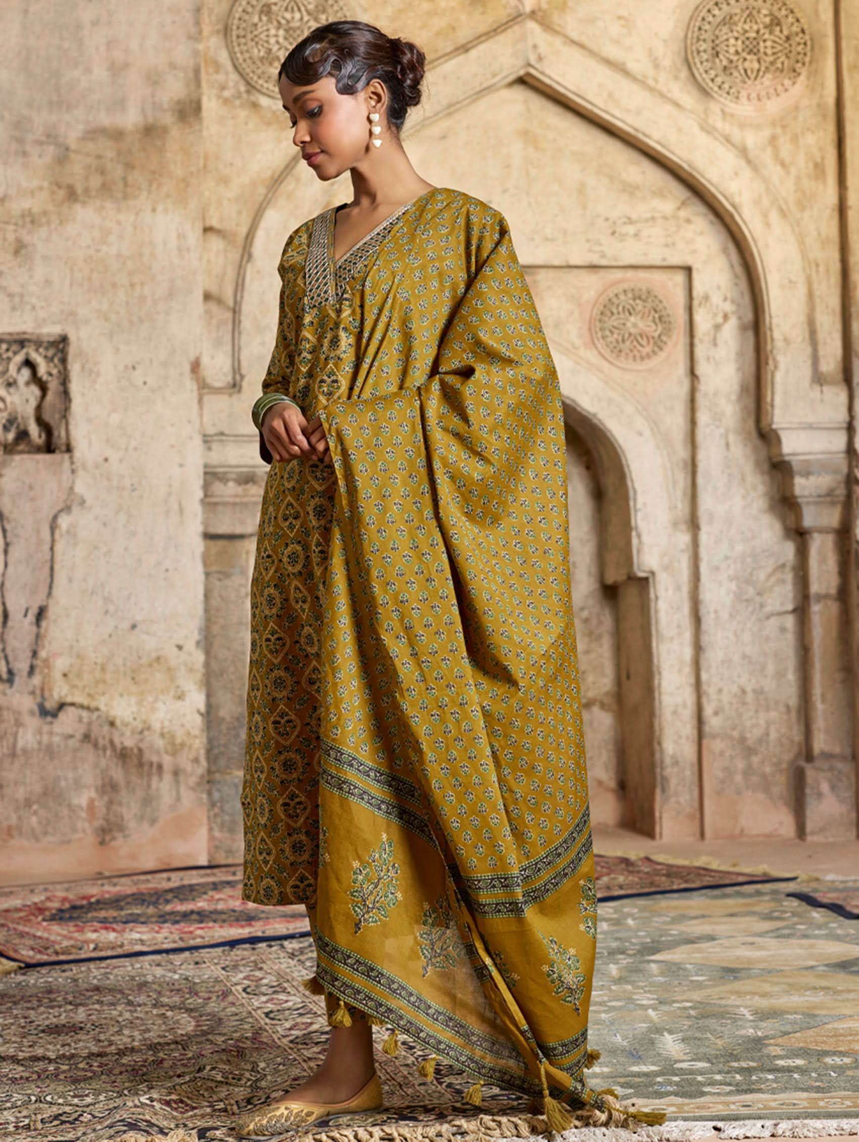 A model wearing a yellow and green embroidered pure cotton suit set with a kurta, pants, and a dupatta.