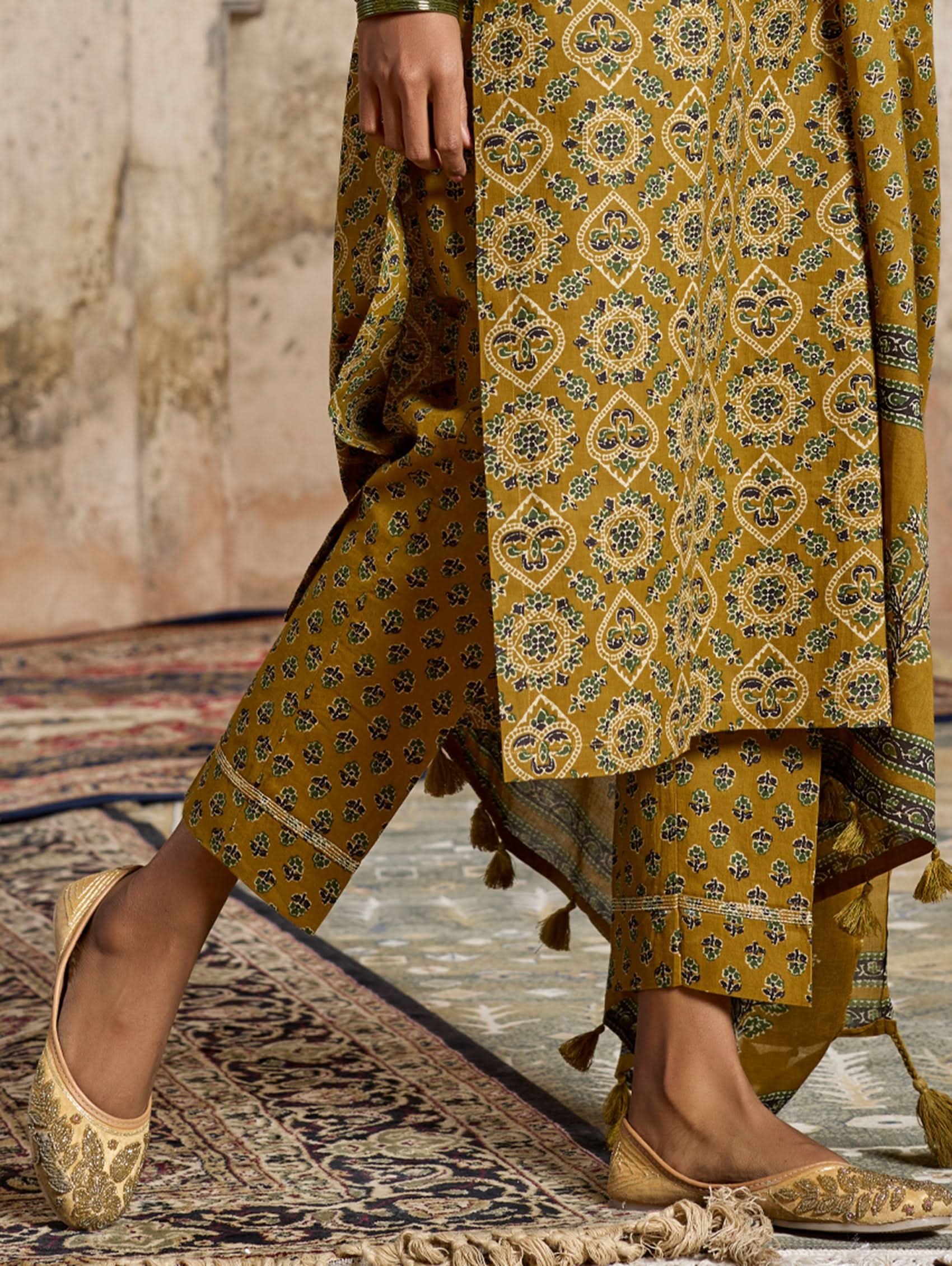 A model wearing a yellow and green embroidered pure cotton suit set with a kurta, pants, and a dupatta.
