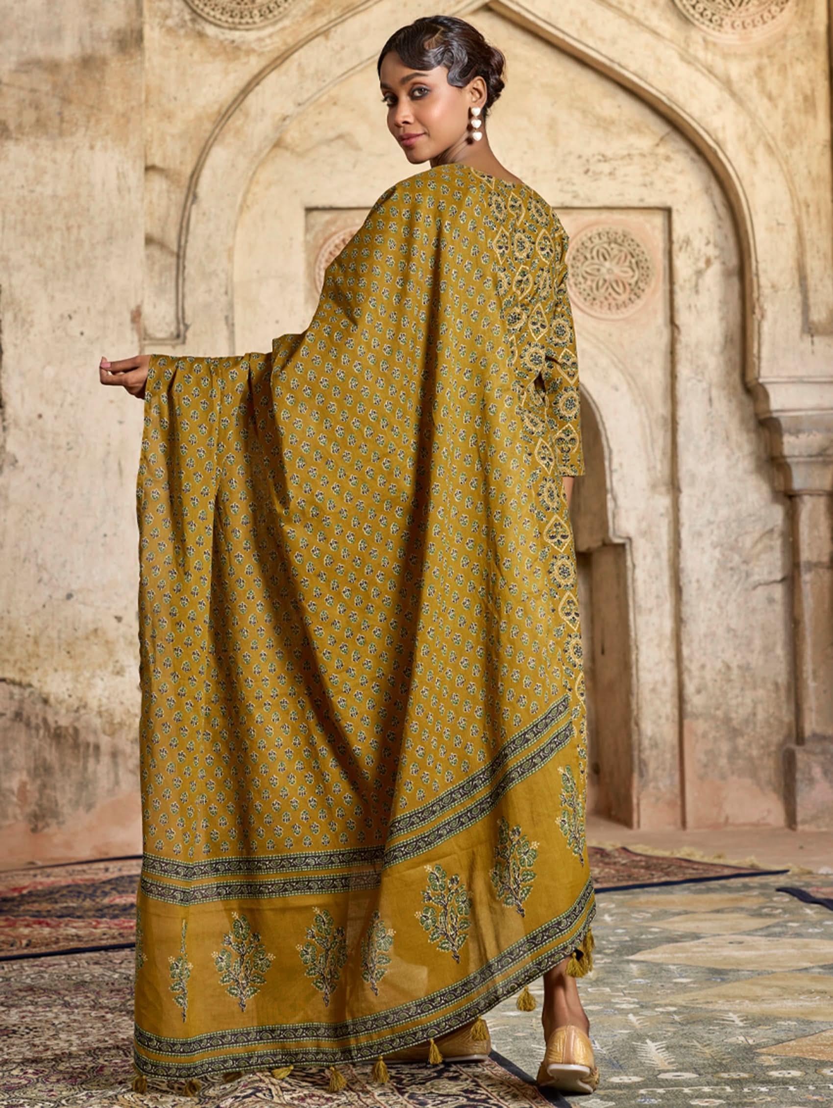 A model wearing a yellow and green embroidered pure cotton suit set with a kurta, pants, and a dupatta.