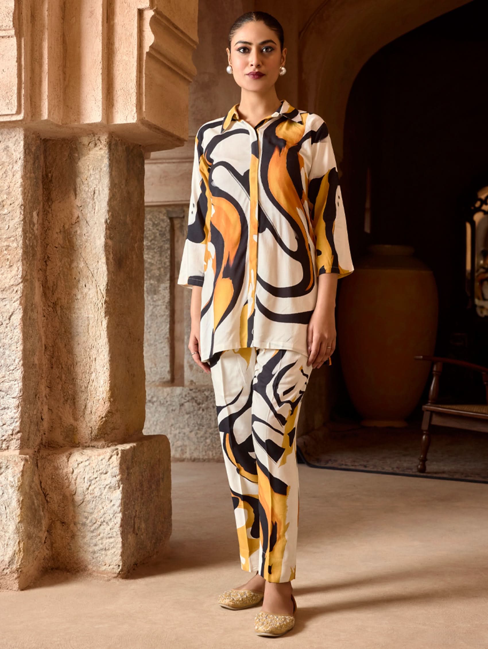 A model wearing a short kurta with a revere collar and three-fourth sleeves, paired with pants that have partially elasticated waistband and pockets on either side. The fabric is digitally printed viscose rayon.