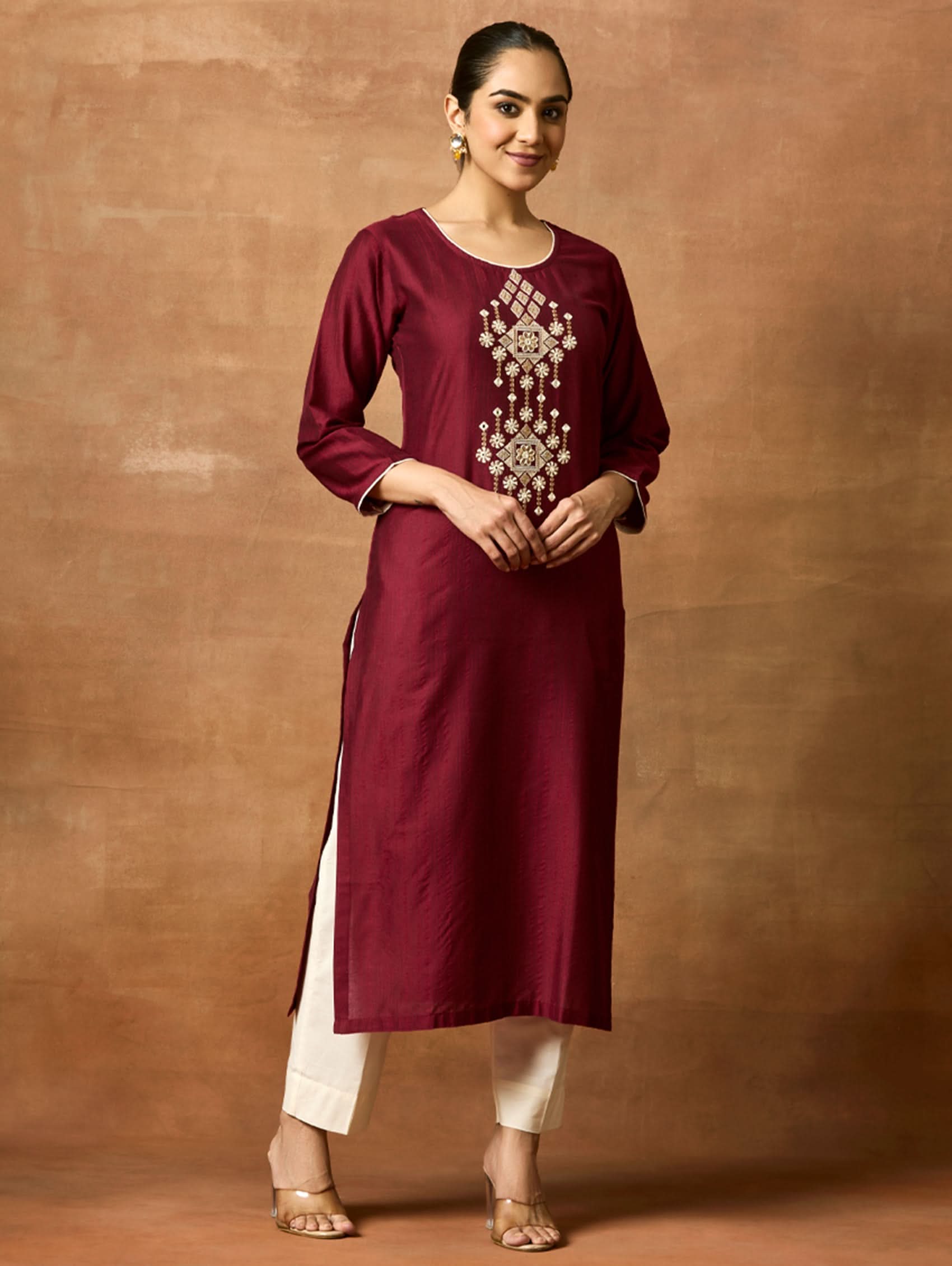 A woman plus size model wearing a maroon colored, computerised thread embroidered pure cotton kurta with round neckline and three-fourth sleeves.