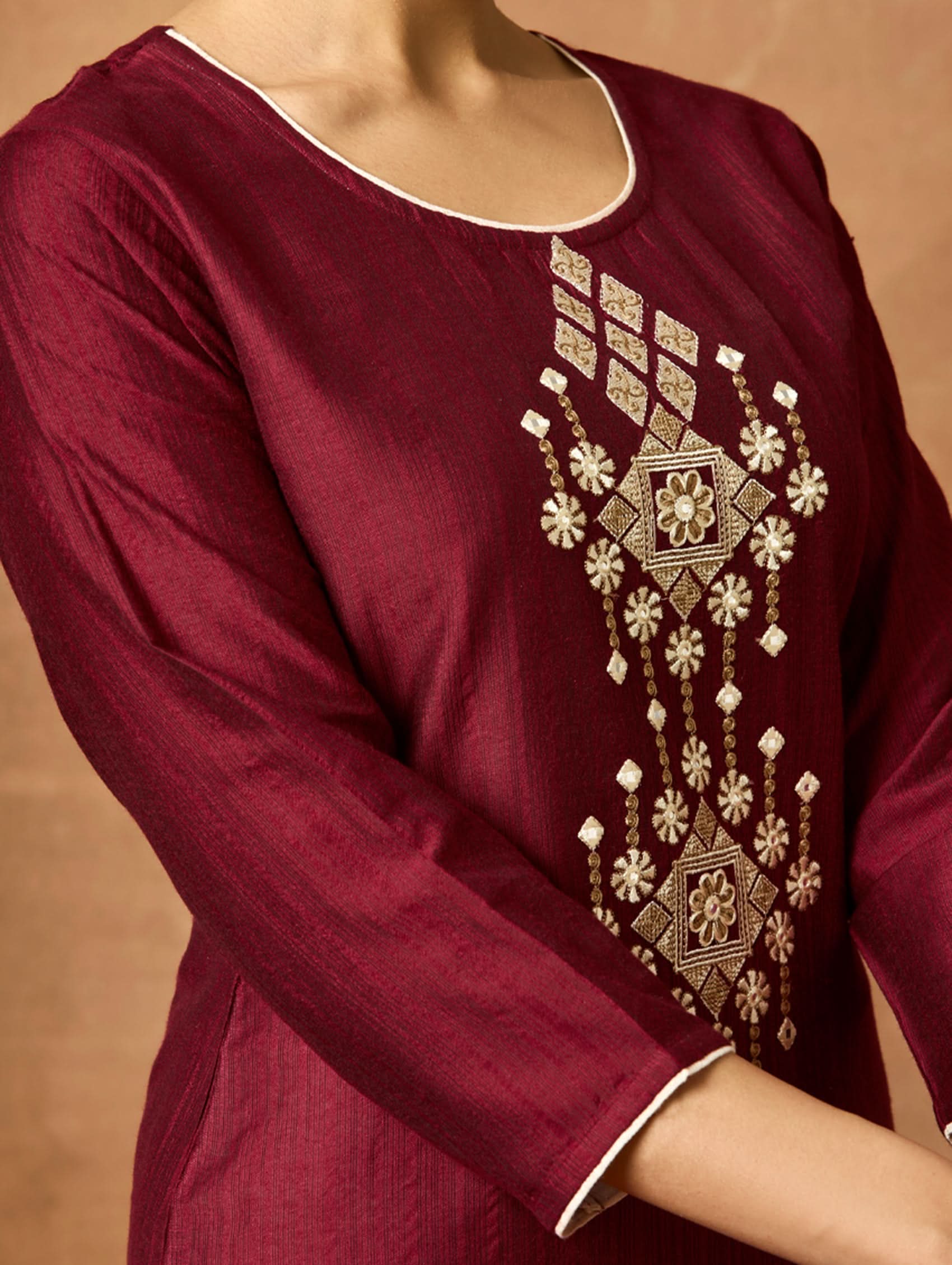 Maroon kurta with intricate gold embroidery on a plain background.