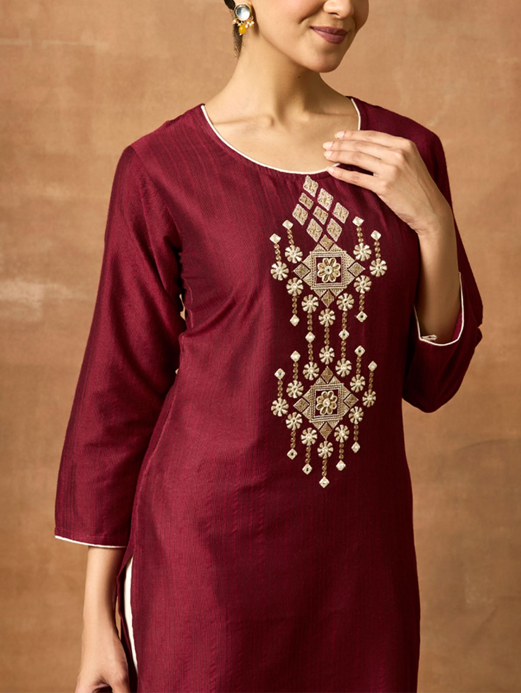 Maroon kurta with intricate silver embroidery on a brown background.
