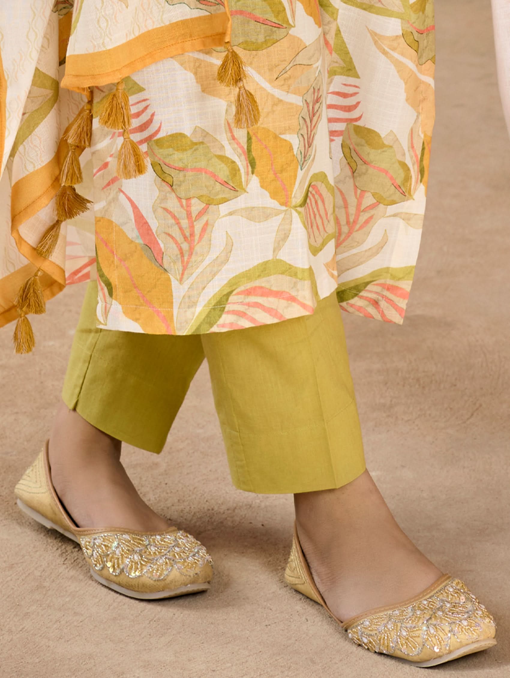 Person wearing yellow pants and decorative shoes, with a patterned shawl.