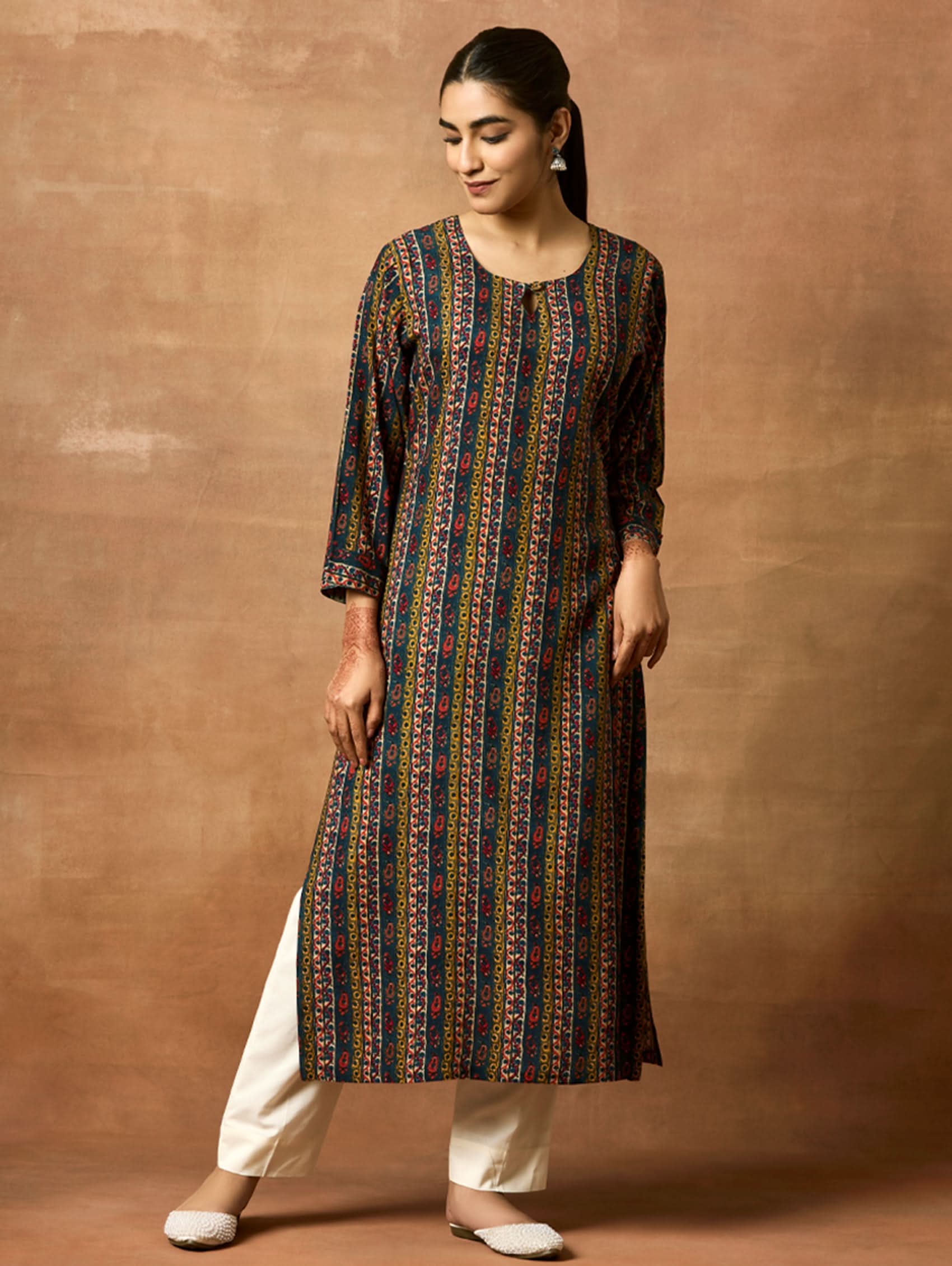 A woman plus size model wearing a printed viscose rayon kurta with a keyhole round neckline, three-fourth sleeves, and side slits. The kurta is in shades of blue and yellow.