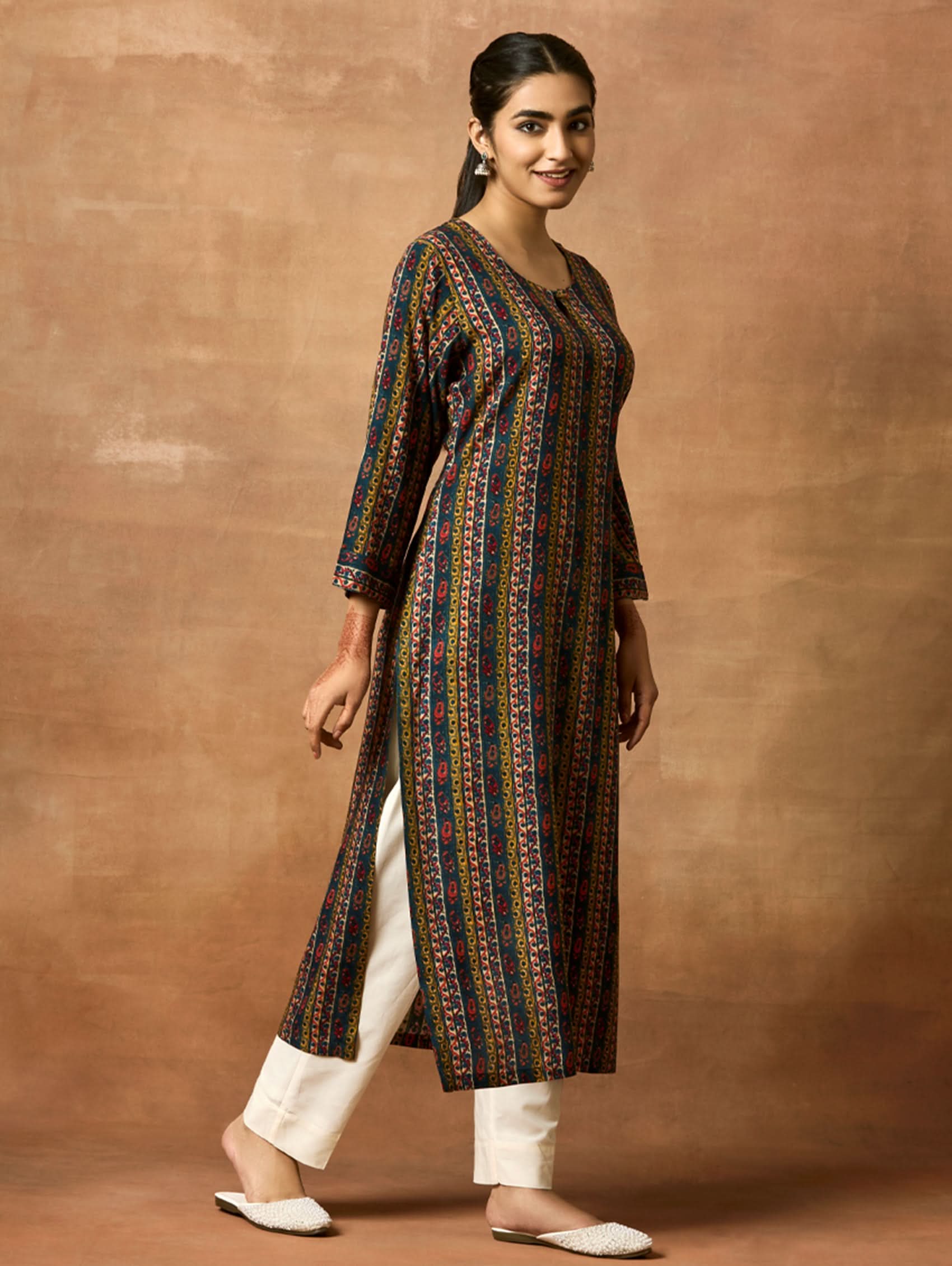 A woman plus size model wearing a printed viscose rayon kurta with a keyhole round neckline, three-fourth sleeves, and side slits. The kurta is in shades of blue and yellow.