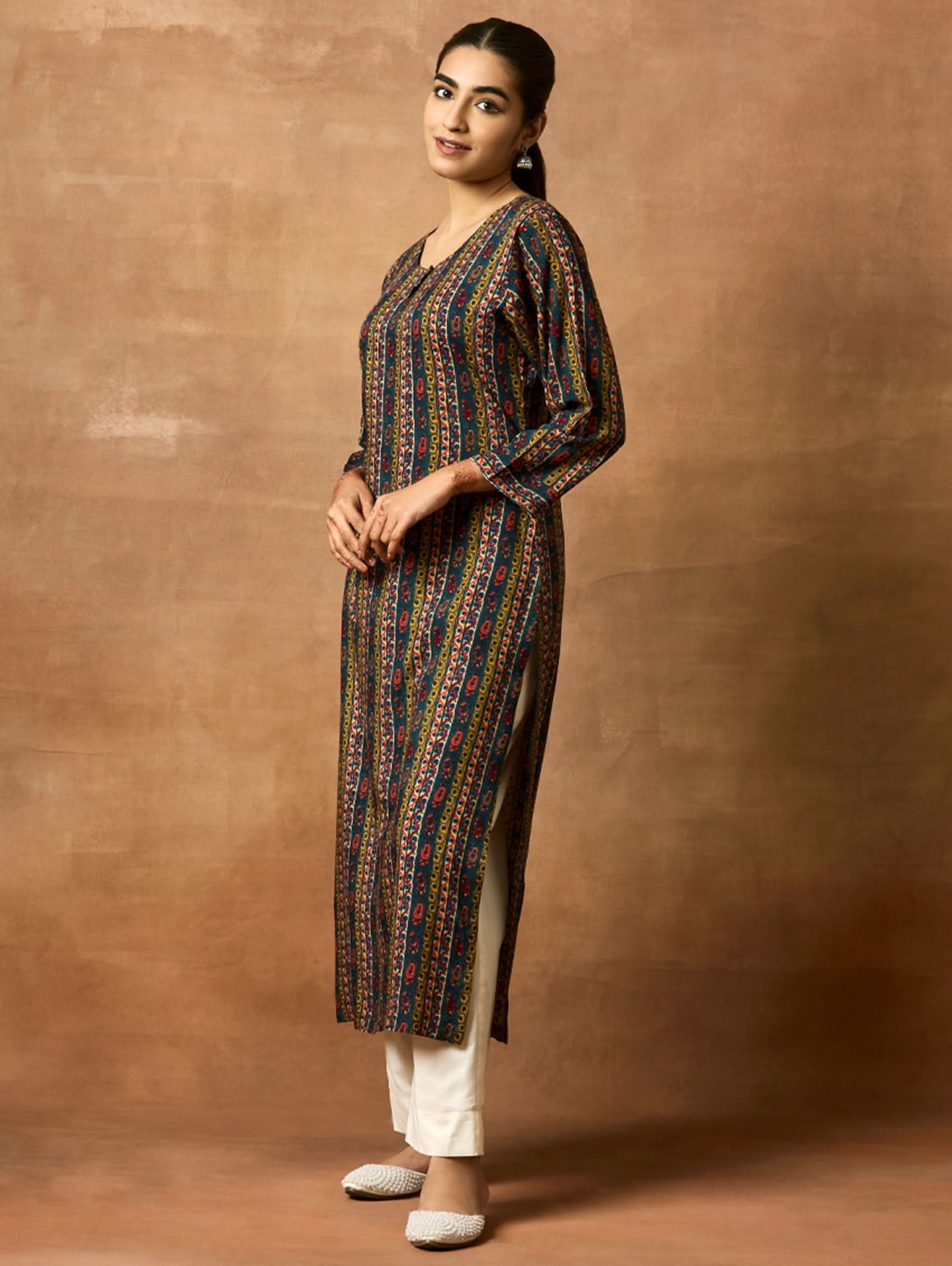 A woman plus size model wearing a printed viscose rayon kurta with a keyhole round neckline, three-fourth sleeves, and side slits. The kurta is in shades of blue and yellow.