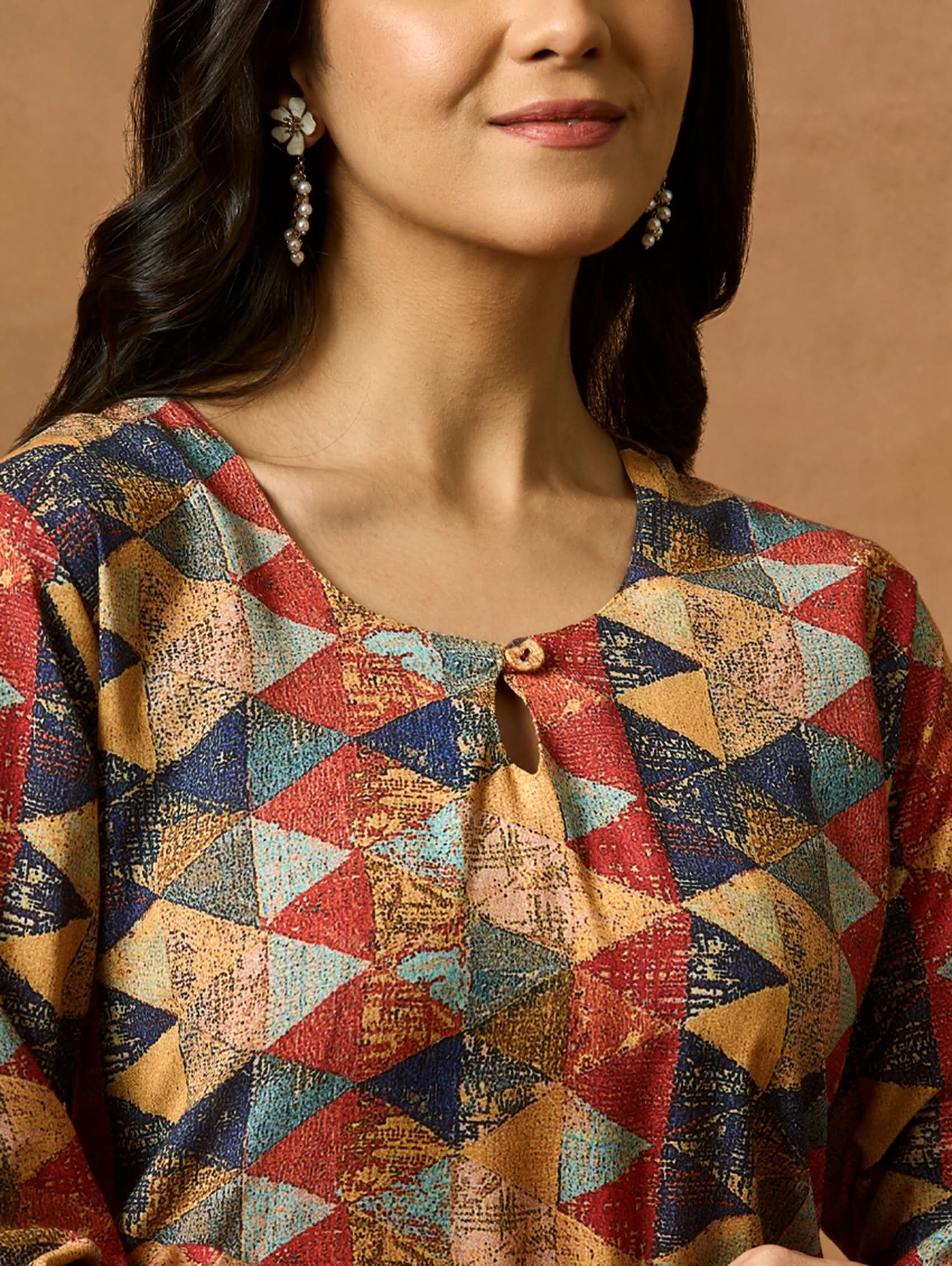 A woman plus size model wearing a multicolored geometric patterned kurta with round neckline and three-fourth sleeves.