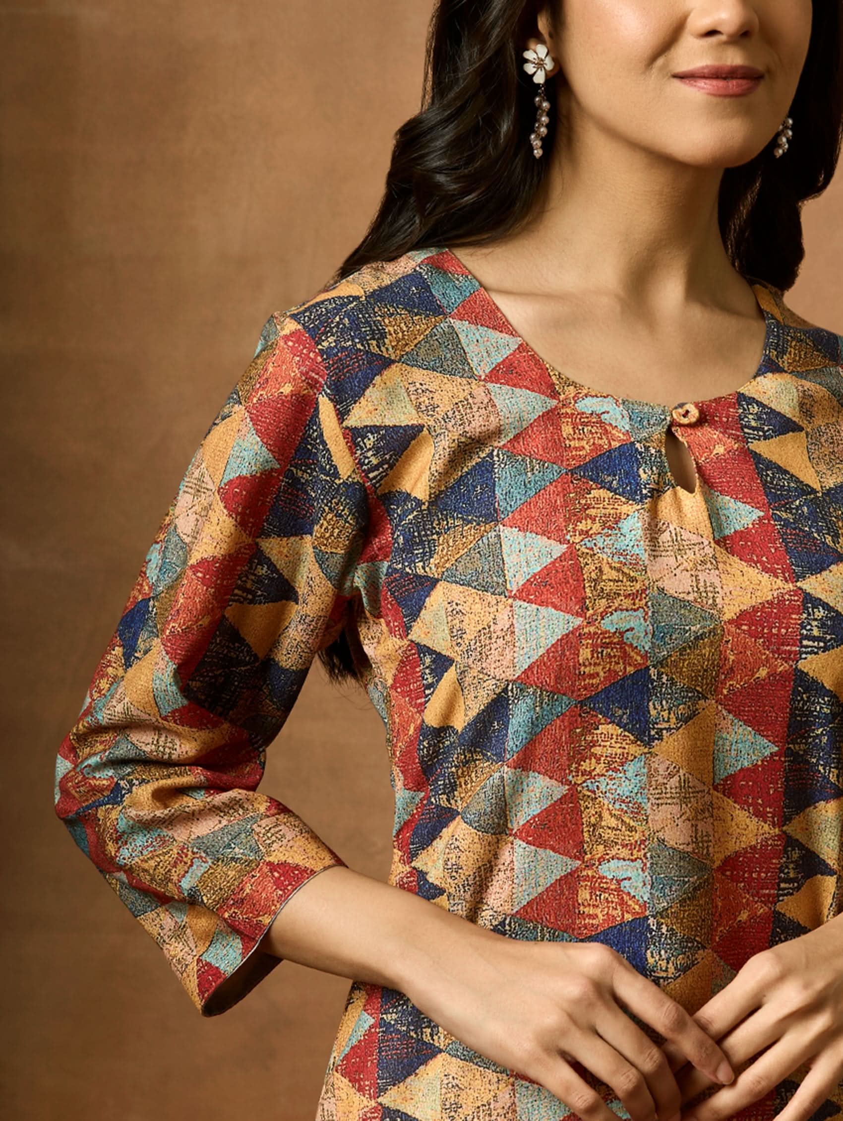 A woman plus size model wearing a multicolored geometric patterned kurta with Keyhole round neckline and three-fourth sleeves.